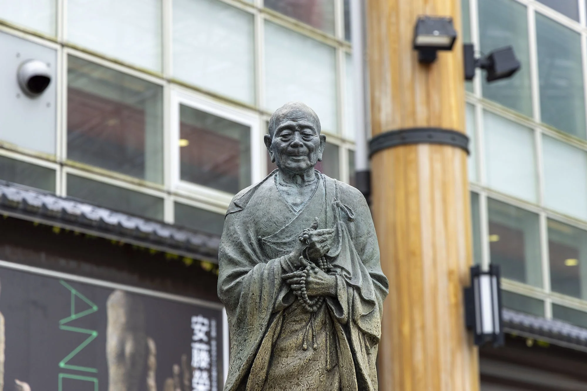 Close-up of the bronze statue of Buddhist monk Gyōki outside Kintetsu Nara Station, showing his robes, prayer beads, and gentle expression.