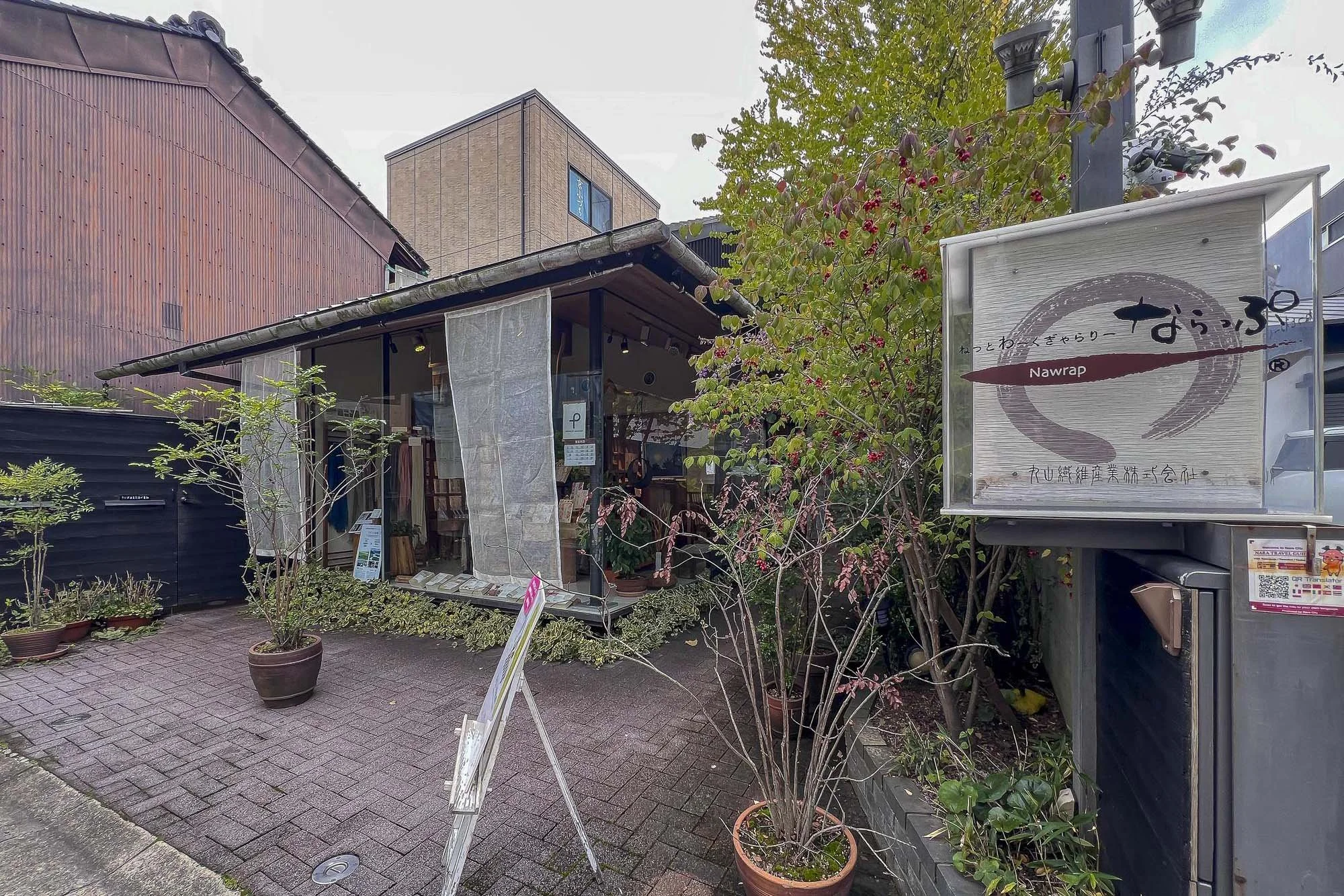 Small building with outdoor plants and a sign that reads 'Nawrap' in Japanese and English, decorated in traditional style.