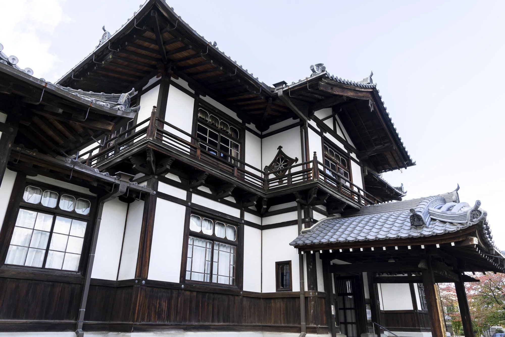 Traditional Japanese building with dark wooden beams, white walls, and tiled roof with ornate decorations.