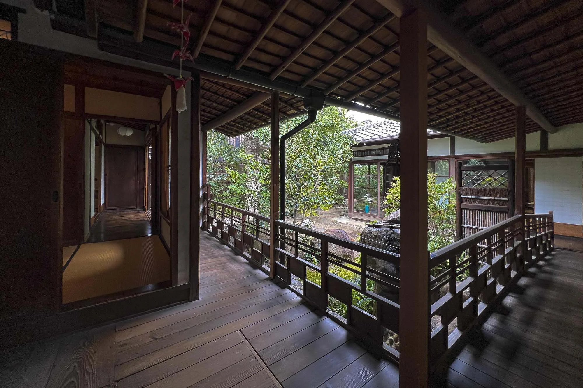 View of a traditional Japanese-style wooden porch with a garden and rocks outside, including sliding doors and a garden path.