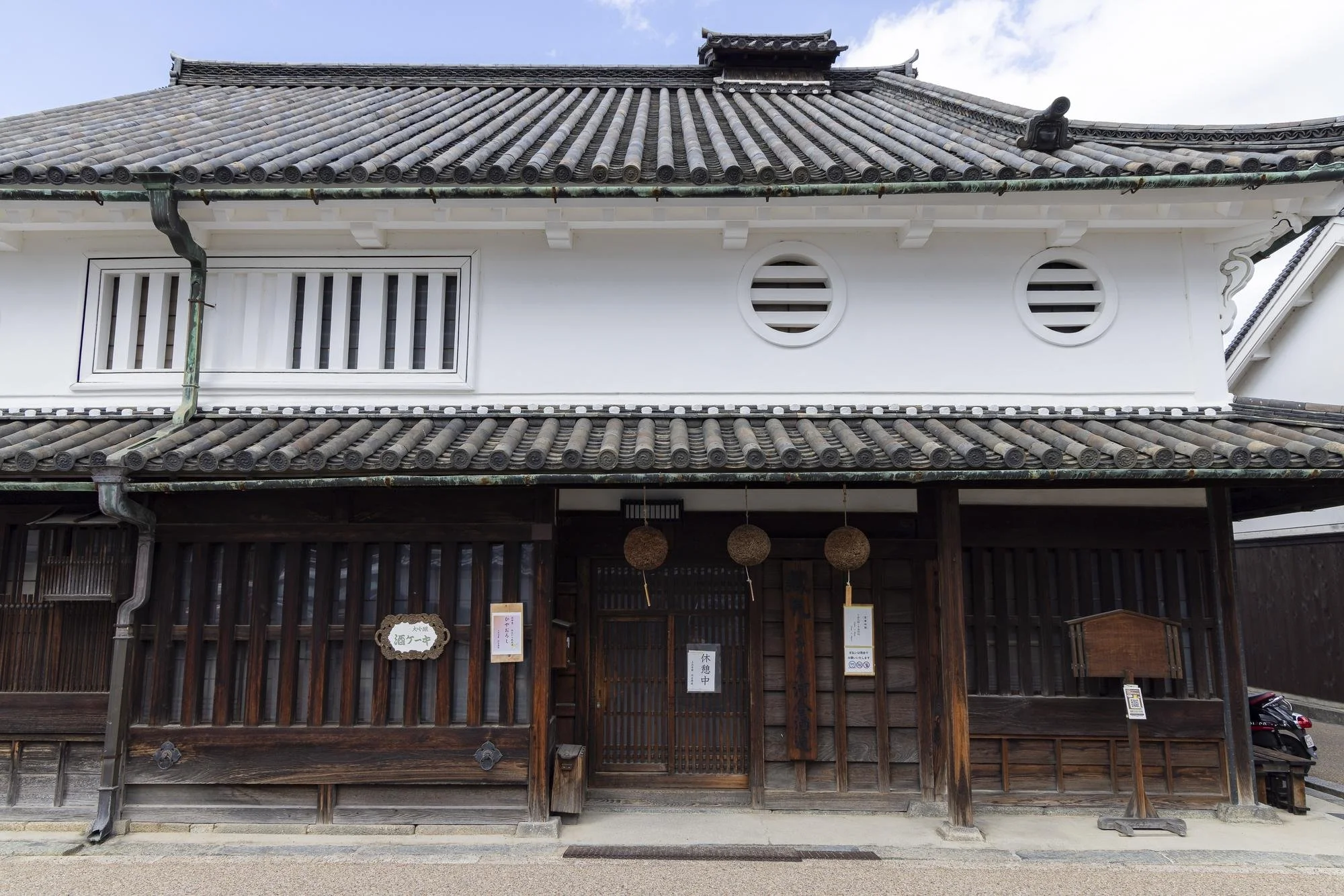 Traditional Japanese building with wooden facade and tiled roof, featuring decorative lanterns hanging at the entrance.