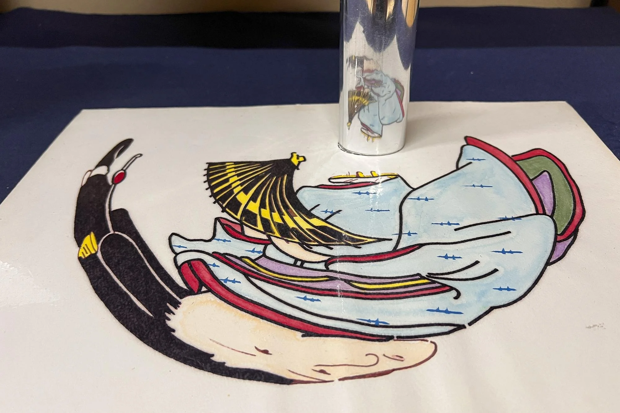 A colorful illustration of a figure lying on a surface with their head resting on their arm, wearing a patterned black hat and a light blue robe with red and purple accents. A silver metal container with a reflection of the same illustration on it is
