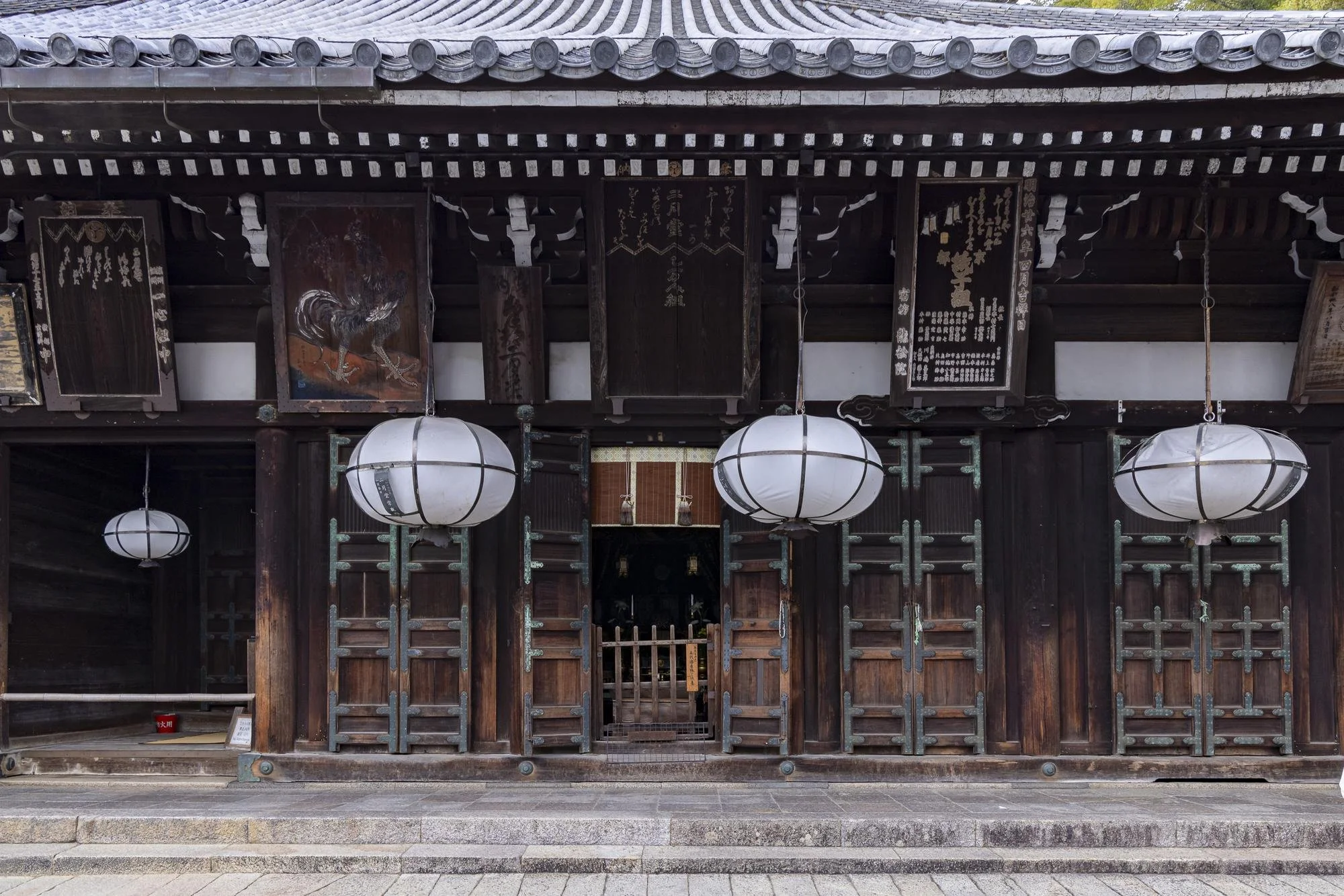 Traditional Japanese wooden temple with large paper lanterns hanging in front, with steps leading up to the entrance and Japanese signage above.