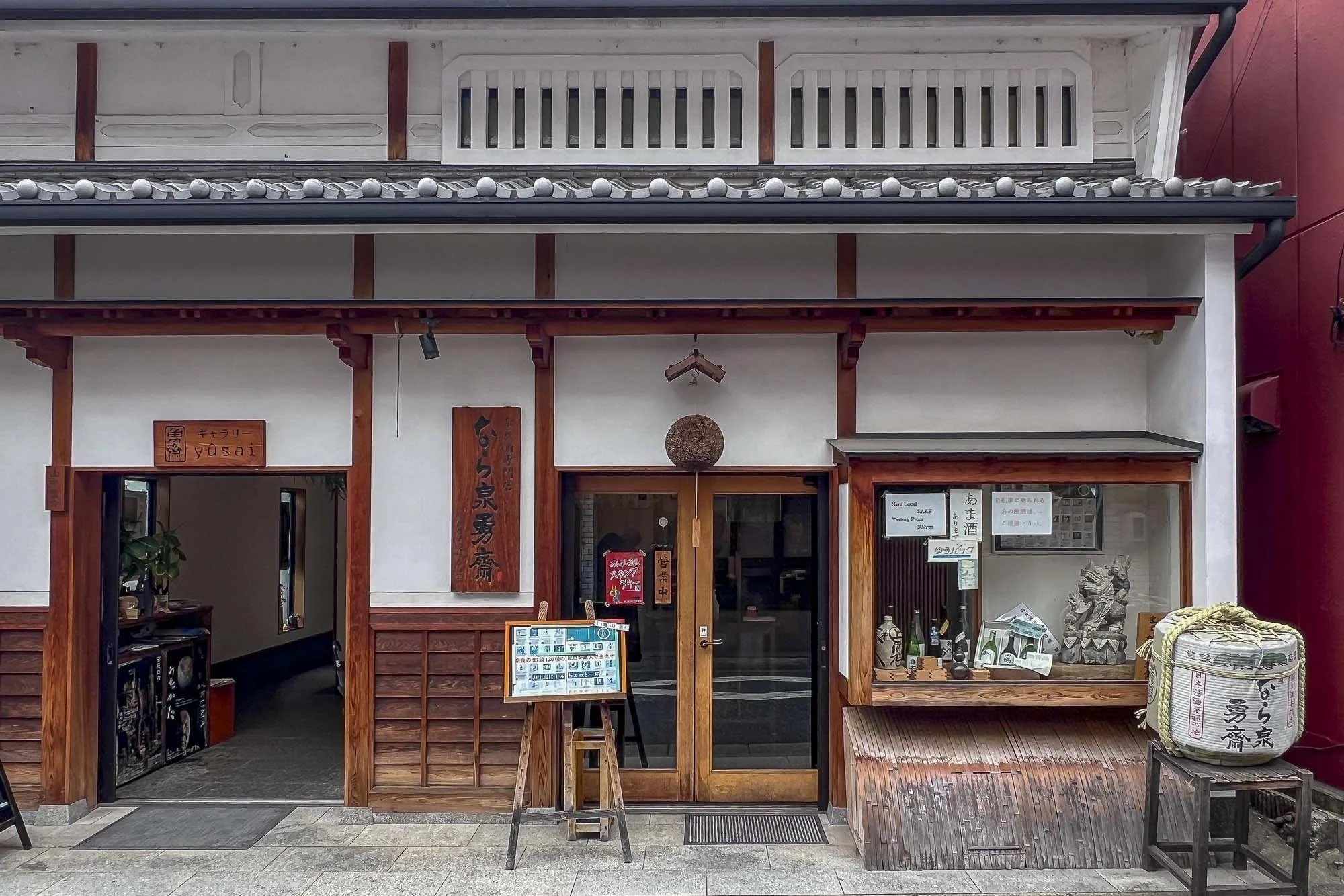 Traditional Japanese storefront with wooden accents, signs, bottles, and decorative elements.
