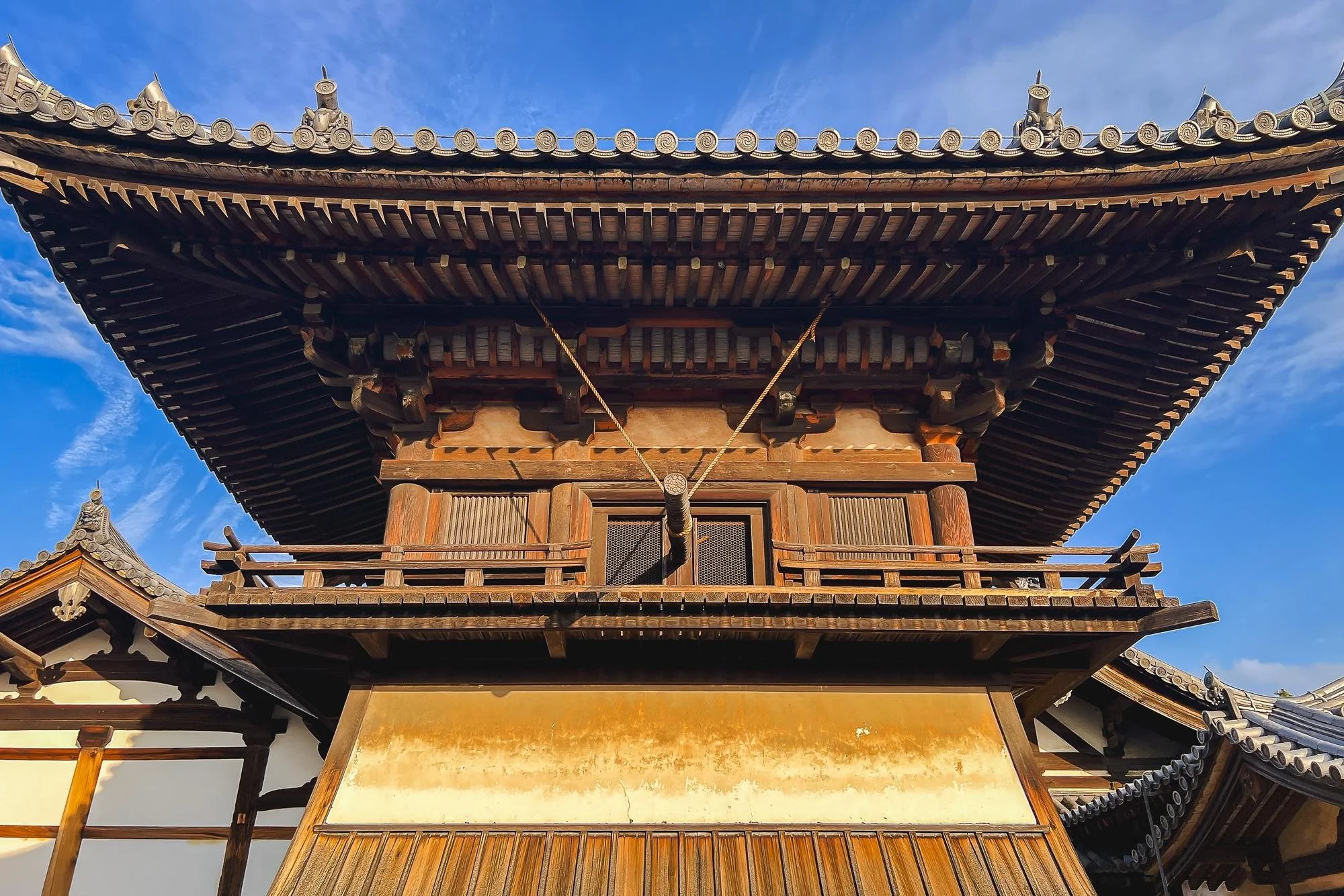 Traditional Japanese wooden temple with tiered roof and intricate detailing, set against a blue sky.
