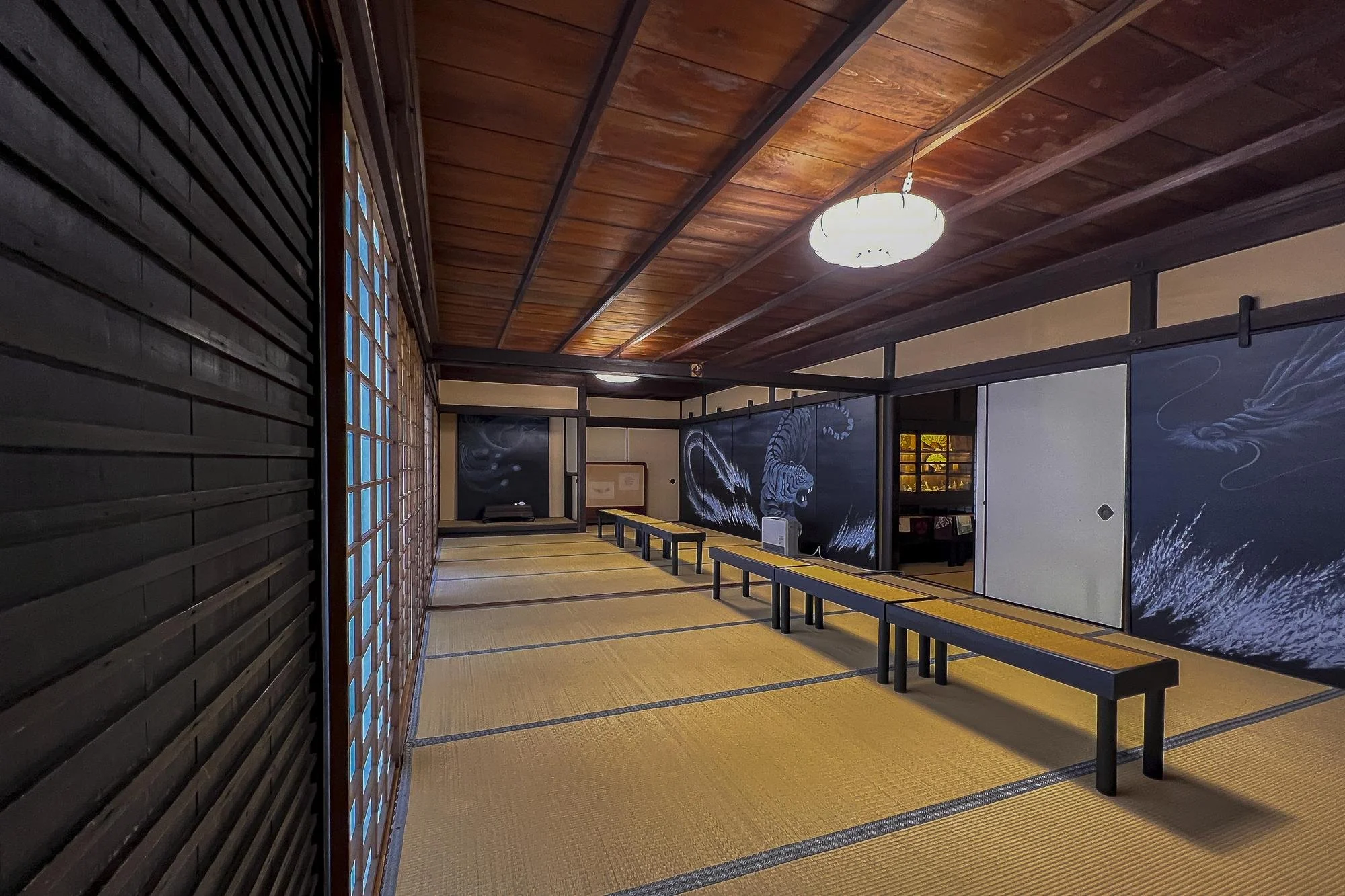 Traditional Japanese-style room with tatami mats, sliding doors, and painted panels of a tiger and dragon.