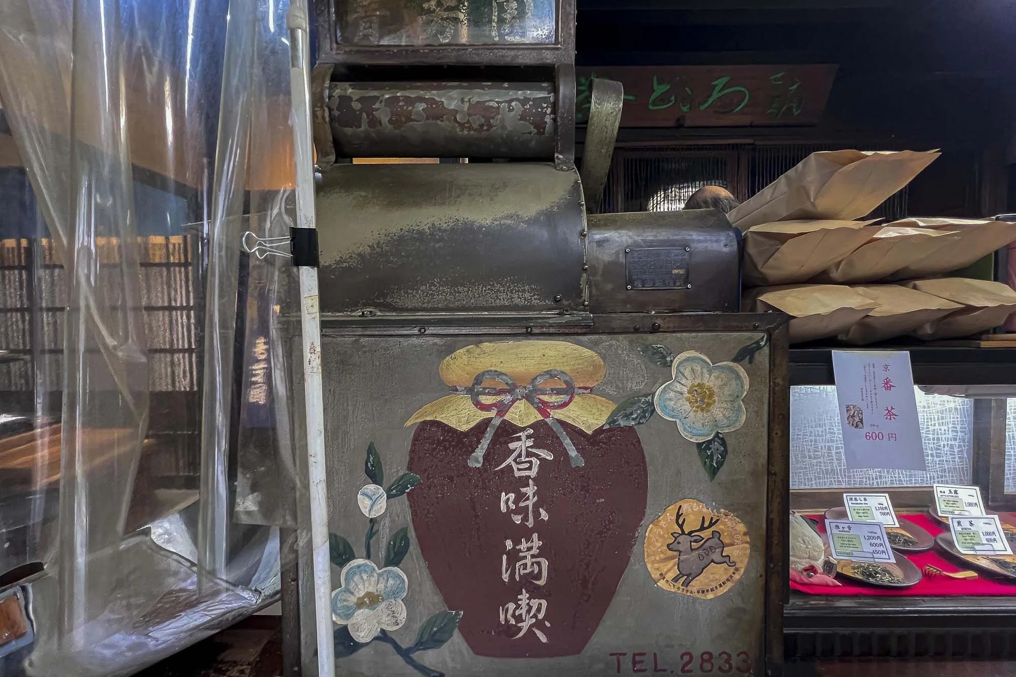 Vintage coffee machine with Japanese characters, decorated with flowers and a reindeer illustration, in a shop display.