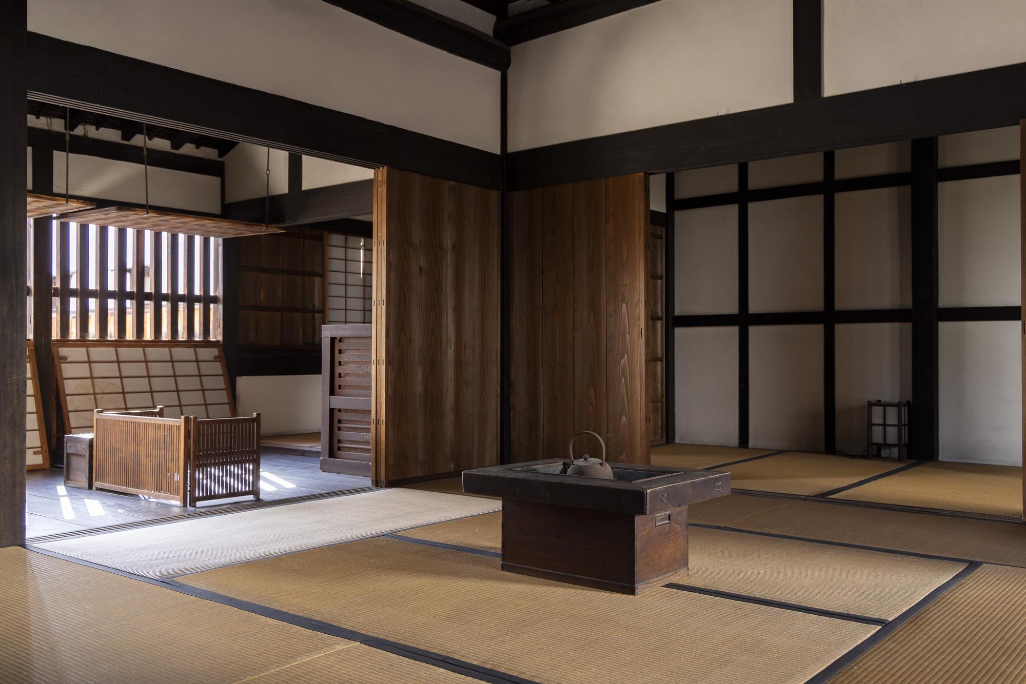 Interior of a traditional Japanese room with tatami mats, wooden sliding doors, and a low table with a kettle on it.
