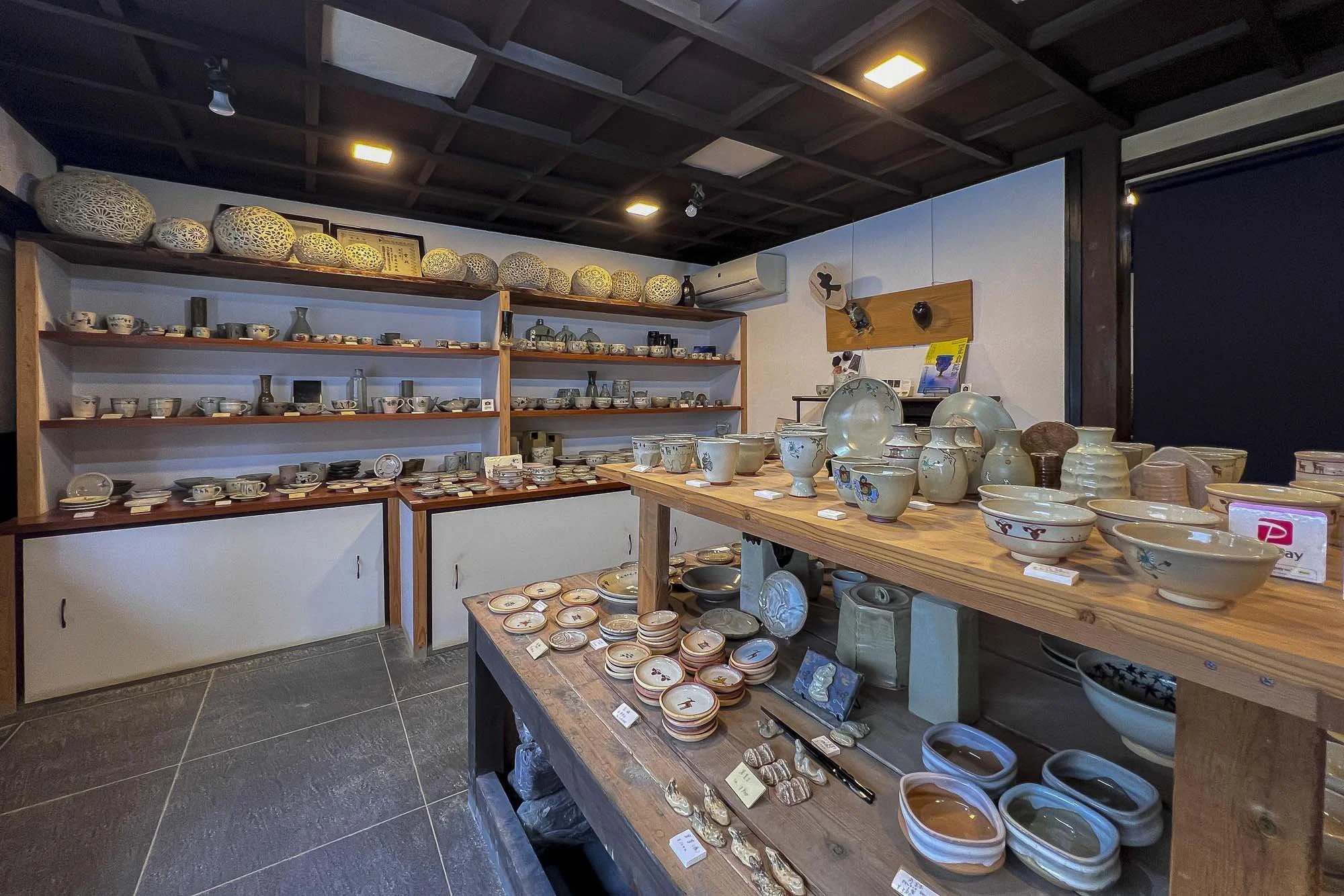 Interior of a pottery shop displaying shelves and tables filled with various ceramic bowls, plates, and vases in different sizes and designs.