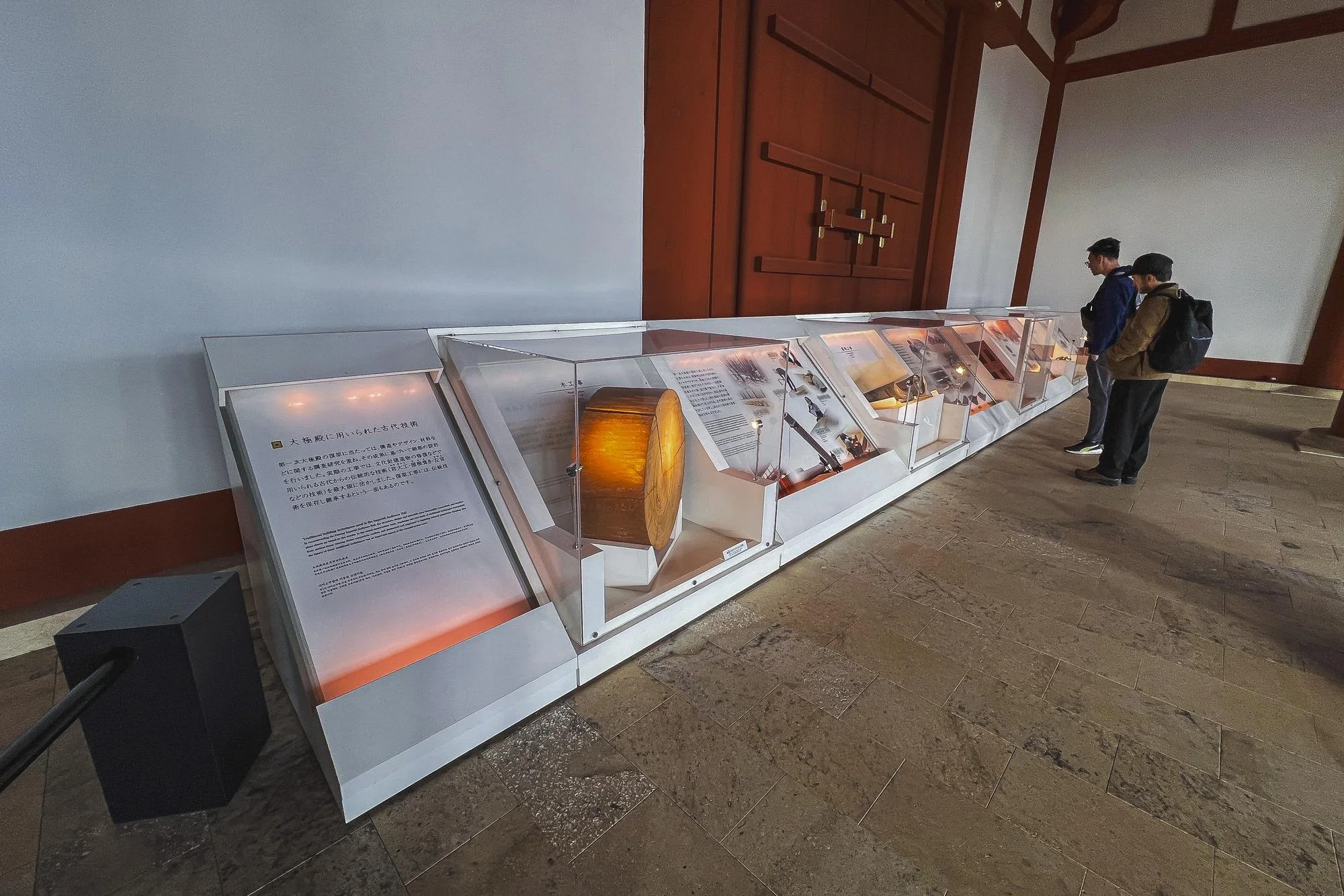 Two people standing next to a display case with artifacts and information panels in a museum.