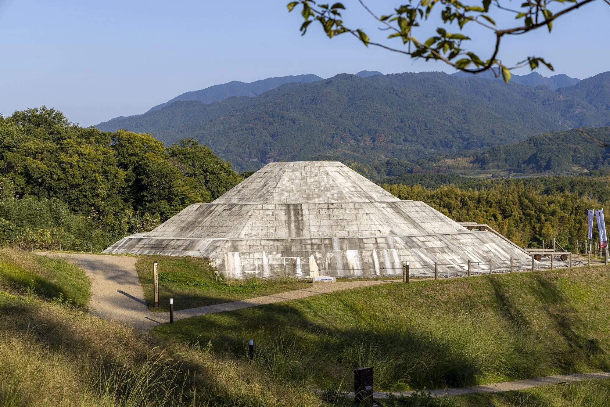 Kengoshizuka Mounded Tomb: A large, modern, pyramid-shaped stone structure surrounded by greenery and mountains in the background.