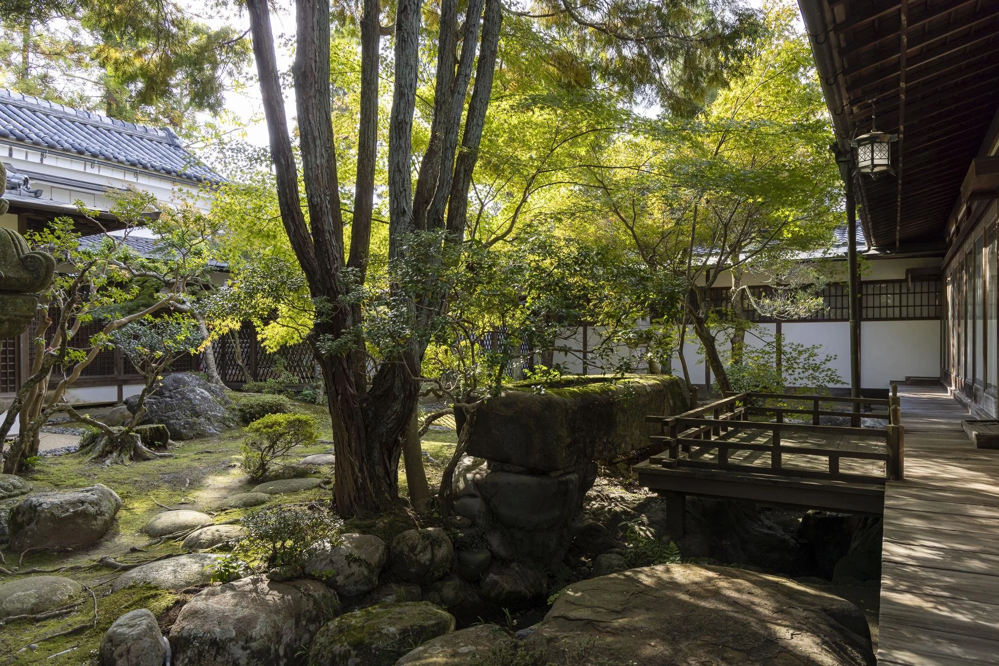 Japanese garden with rocks, trees, traditional wooden structure, and a walkway