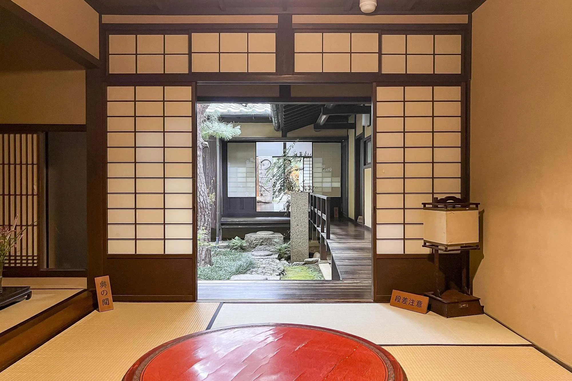 Traditional Japanese room with shoji sliding doors open to a garden courtyard.