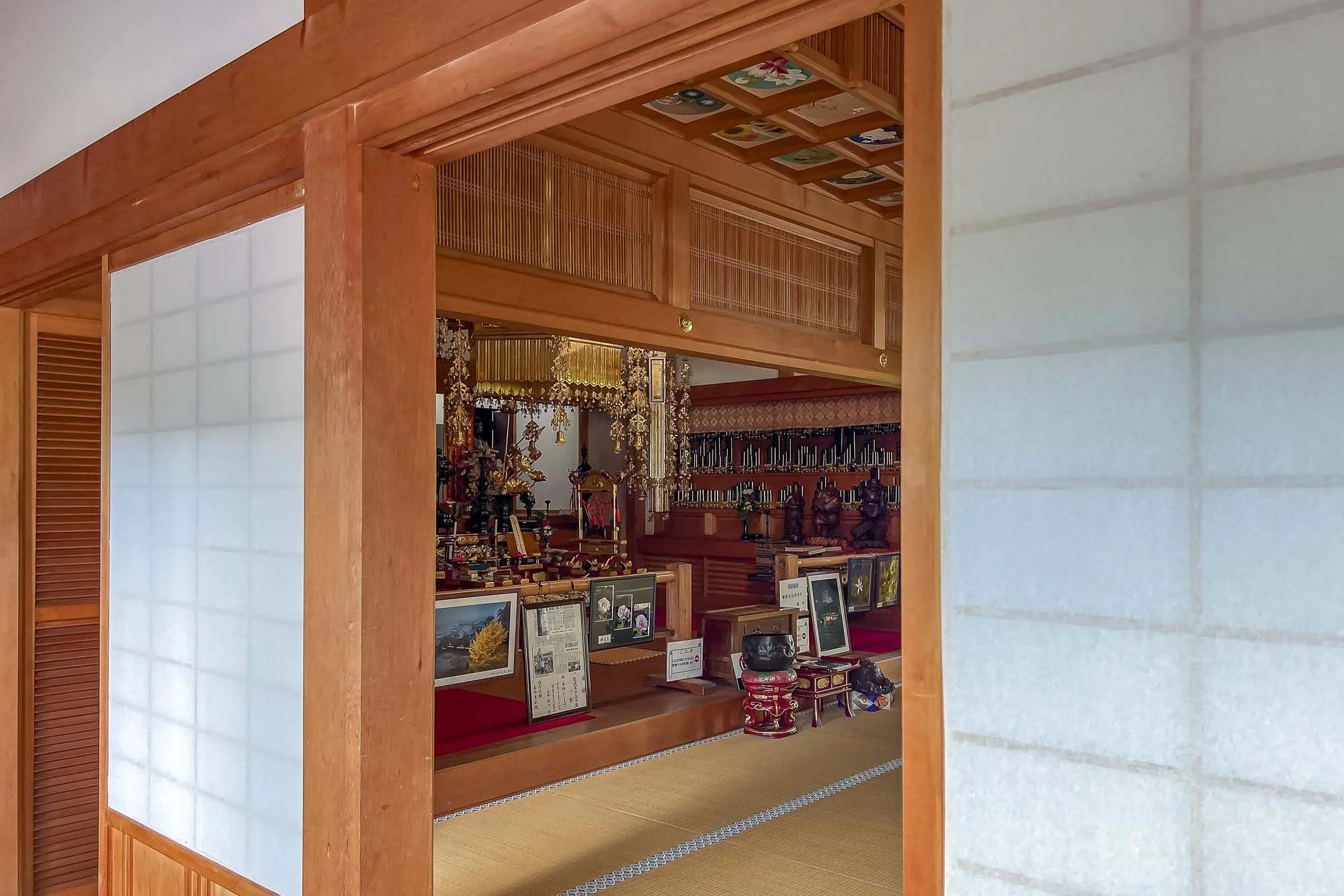 View of a traditional Japanese altar room with wooden accents, displaying religious artifacts, framed pictures, and ornate decorations.