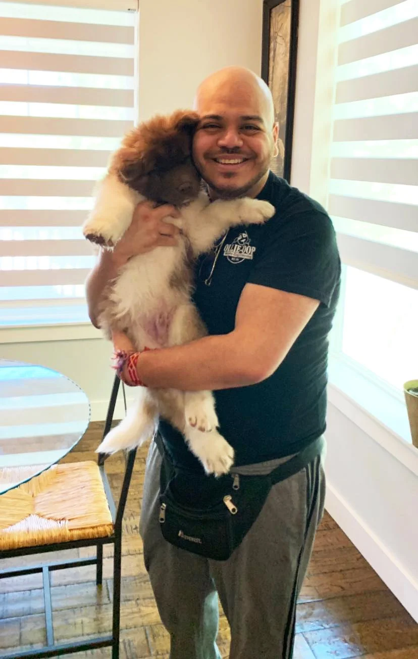 Ollie holding a fluffy puppy inside a home.