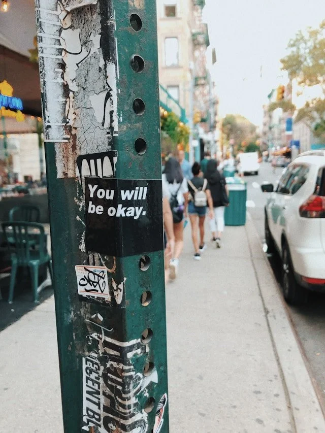 A you will be ok sticker on a metal pillar in a city centre