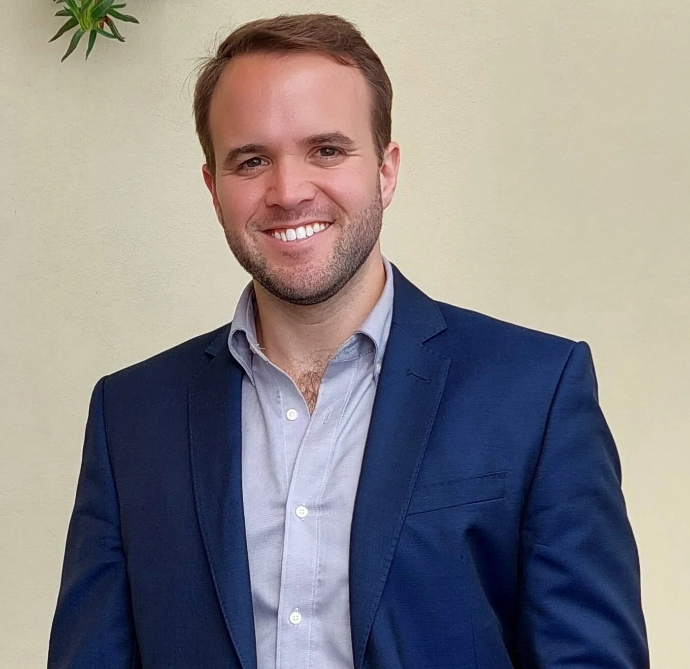 Black and white professional portrait of a smiling man with short hair, wearing a suit jacket and collared shirt.