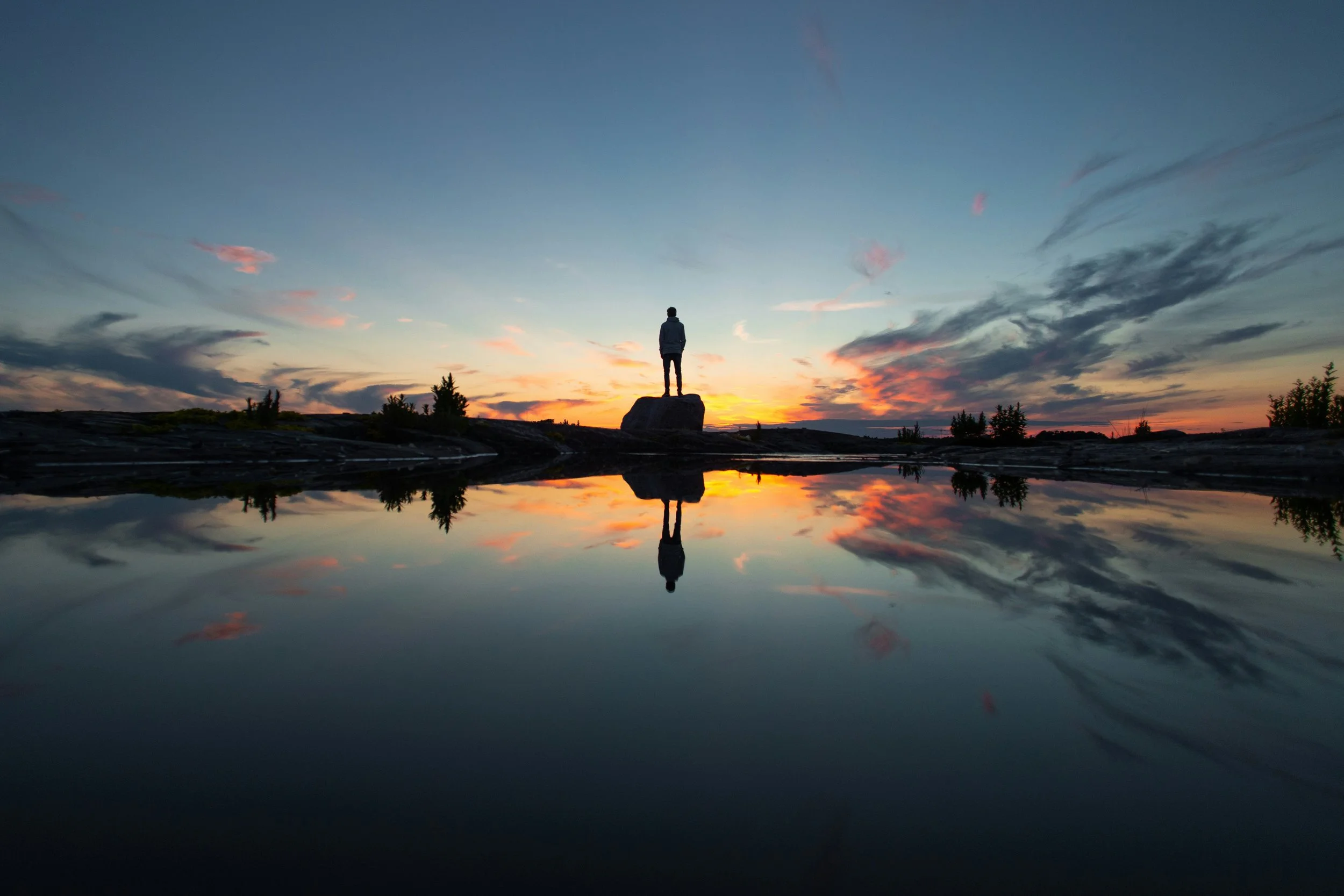 Silhouette of a person on a dock at sunset, reflecting impermanence in Japanese life philosophy