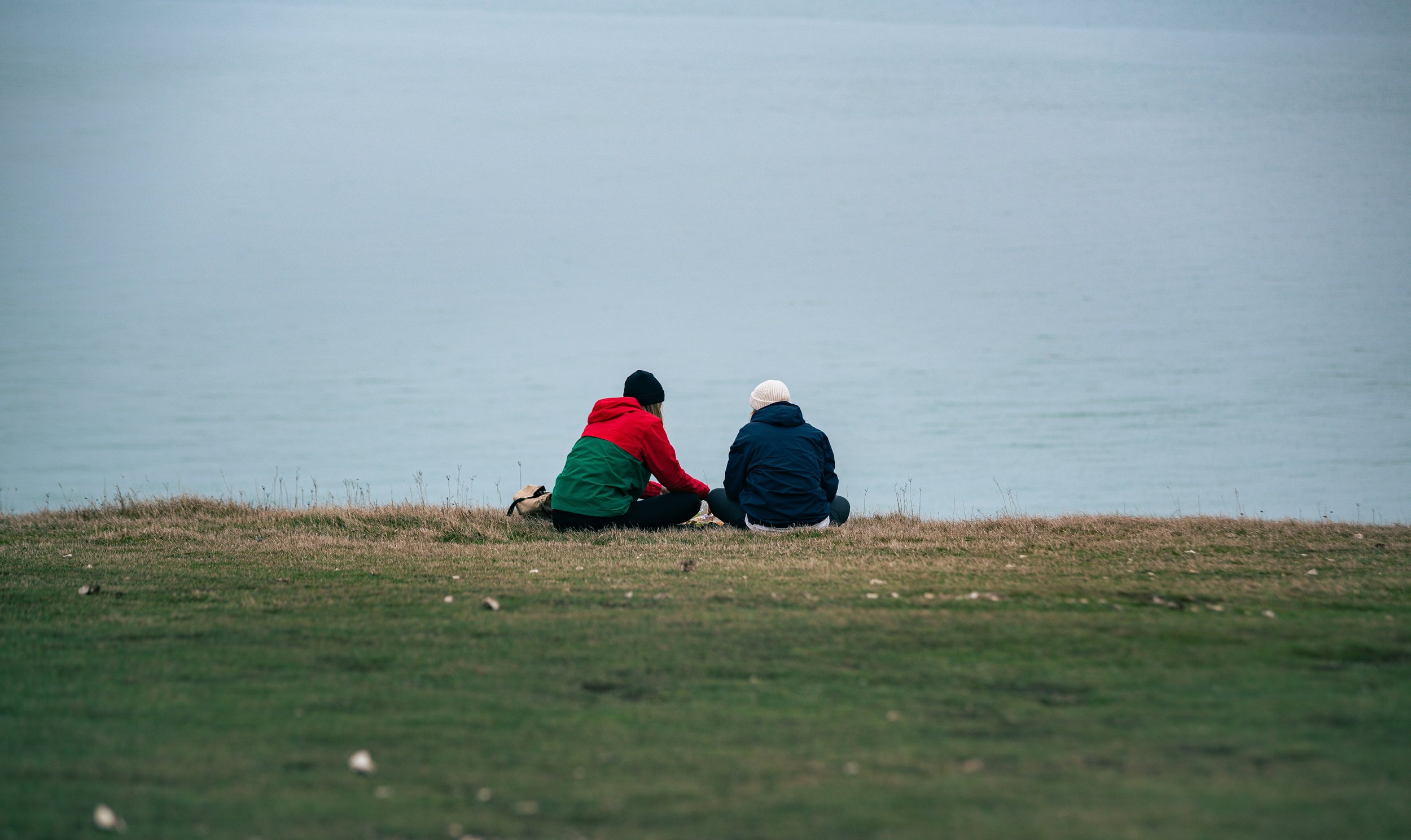 A couple sitting together on a hill at sunset, illustrating how to navigate cuffing season dating and build meaningful winter connections.