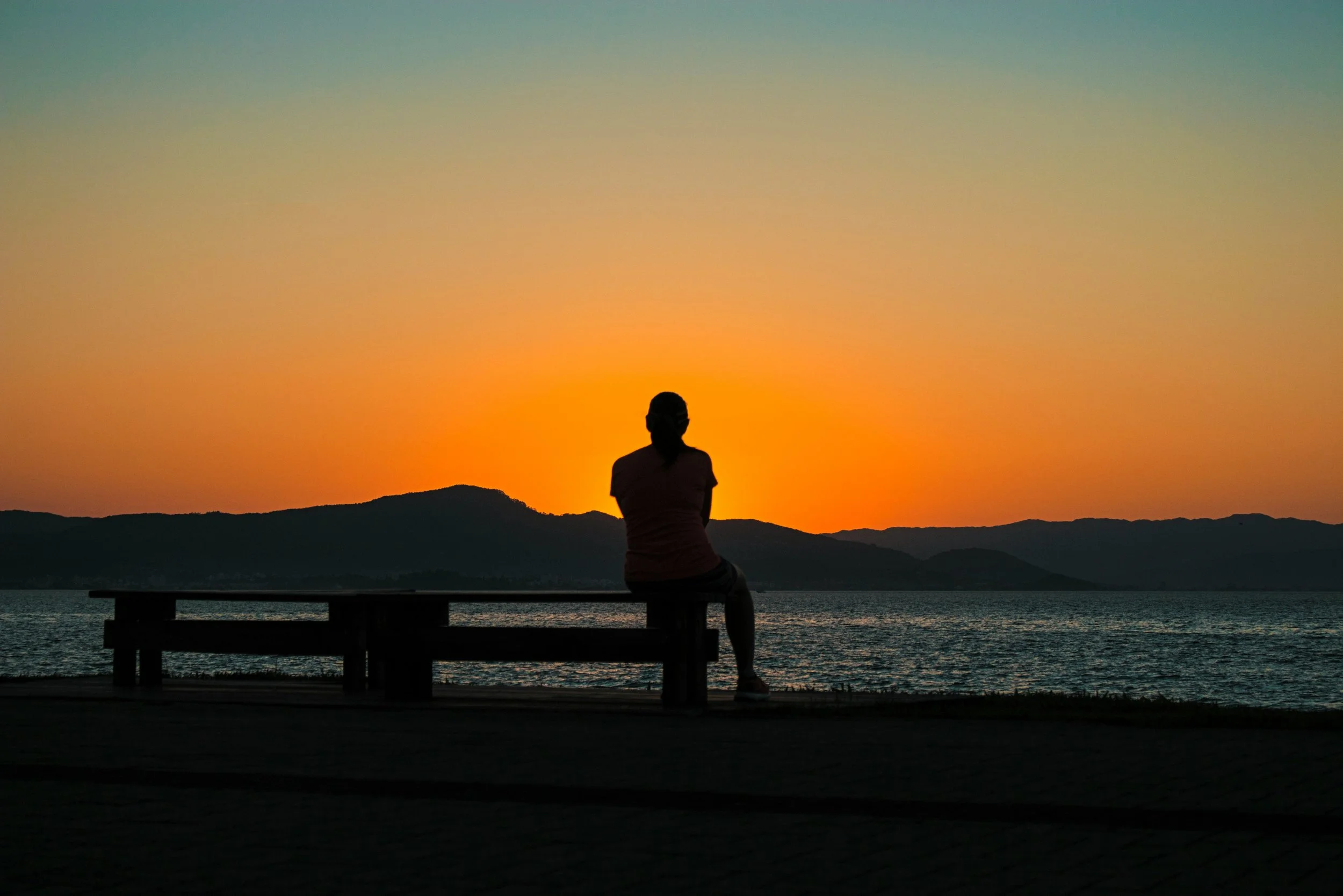 Person sitting alone on a bench at sunset, reflecting on dating app burnout and emotional exhaustion from modern dating