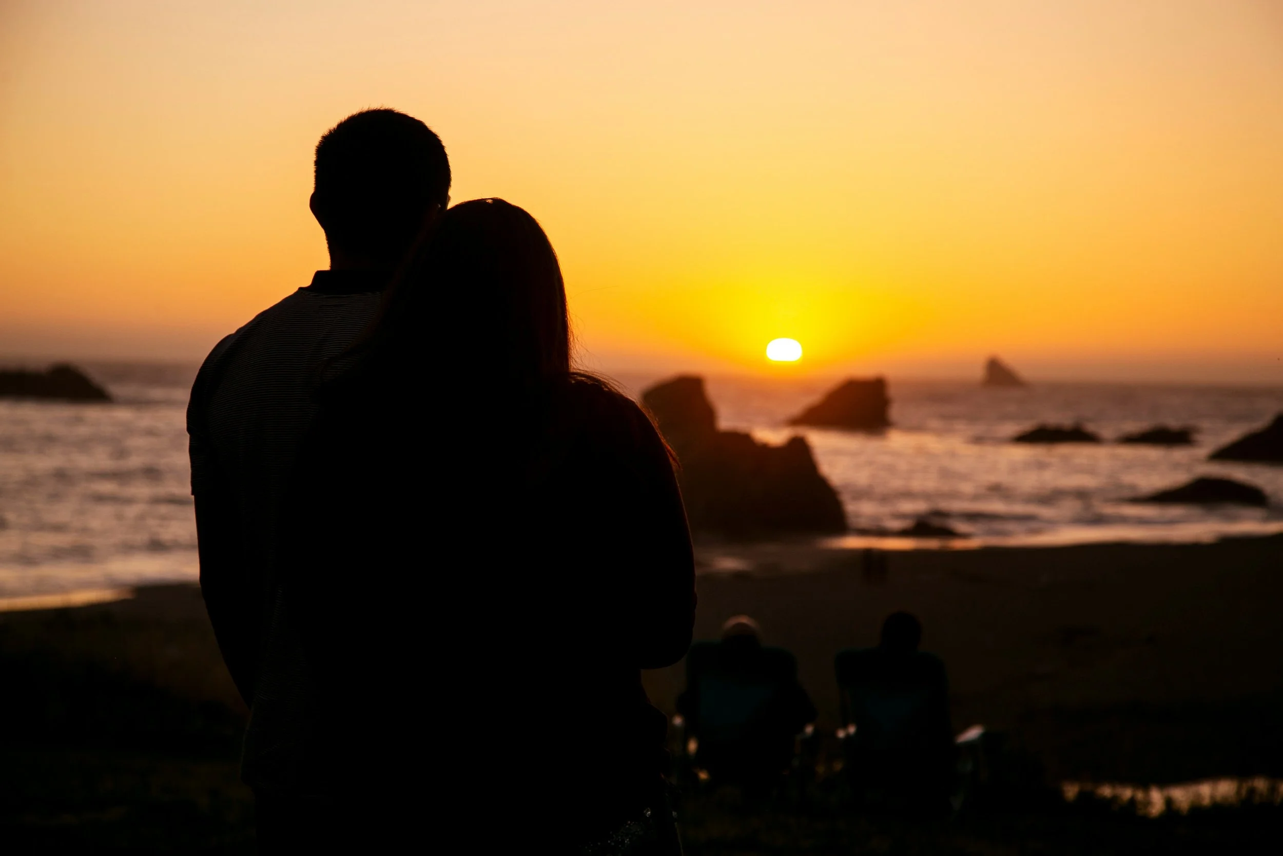 Couple sitting together by the water, reflecting on dating for couples and relationship choices