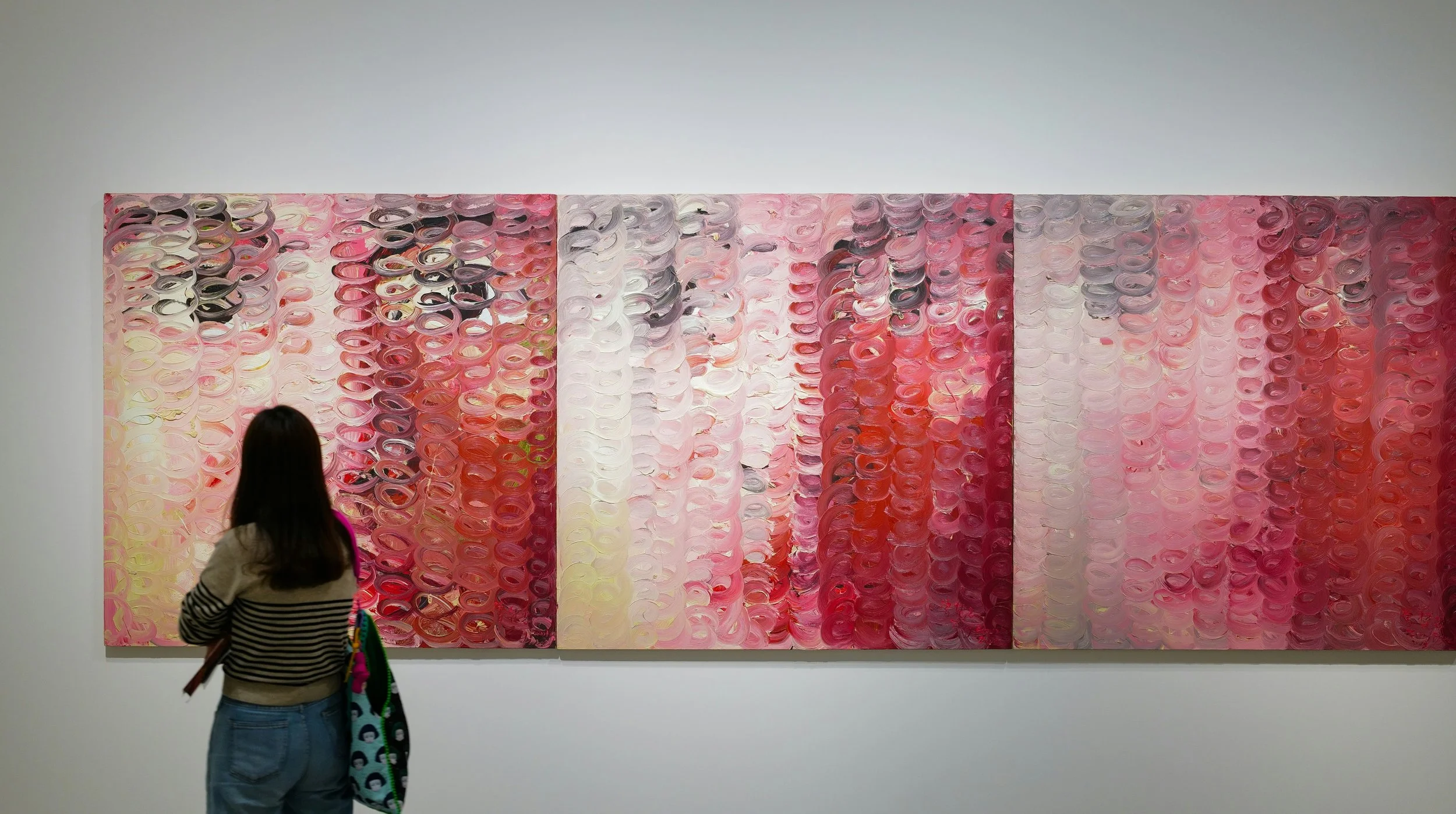 Woman standing before abstract artwork representing layered desire and emotional complexity in multidimensional relationships