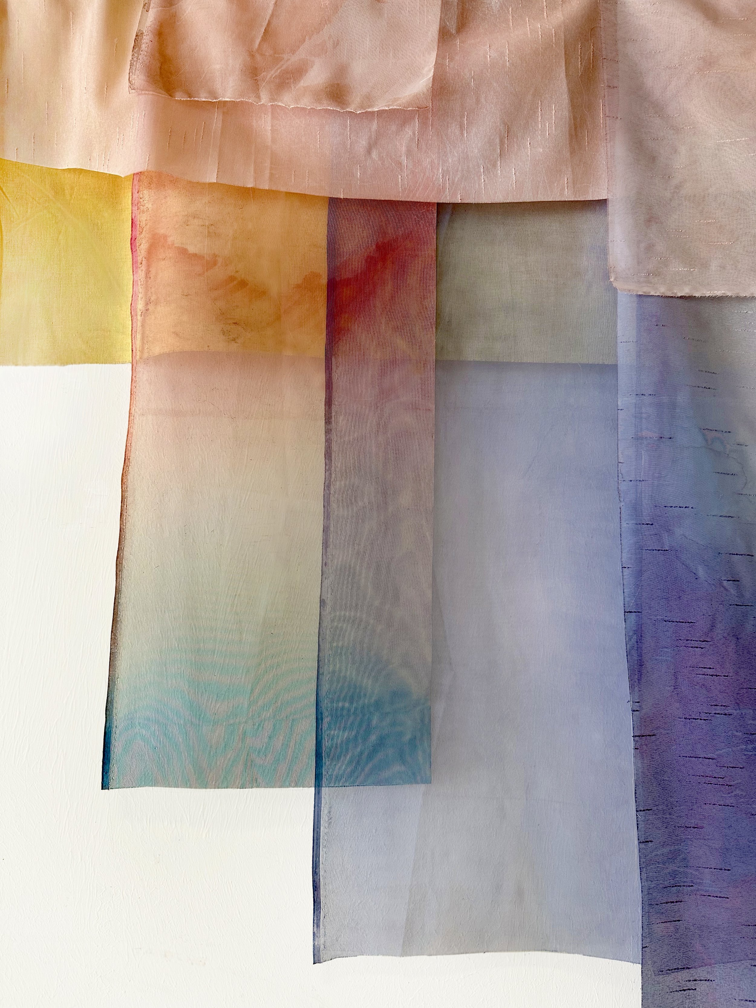 Abstract fabric pieces in pastel colors including pink, yellow, green, blue, and purple, layered and textured.