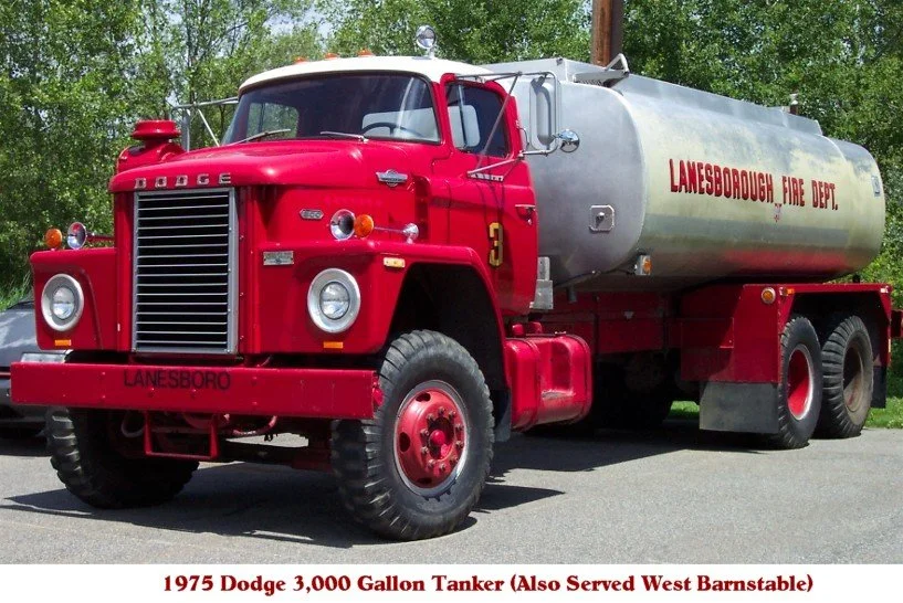 A vintage red Dodge fire truck with a large silver tank, marked 'Lanesborough Fire Dept', parked outdoors on a sunny day.