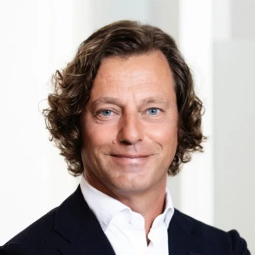 Close-up of a smiling man with dark hair and a mustache.