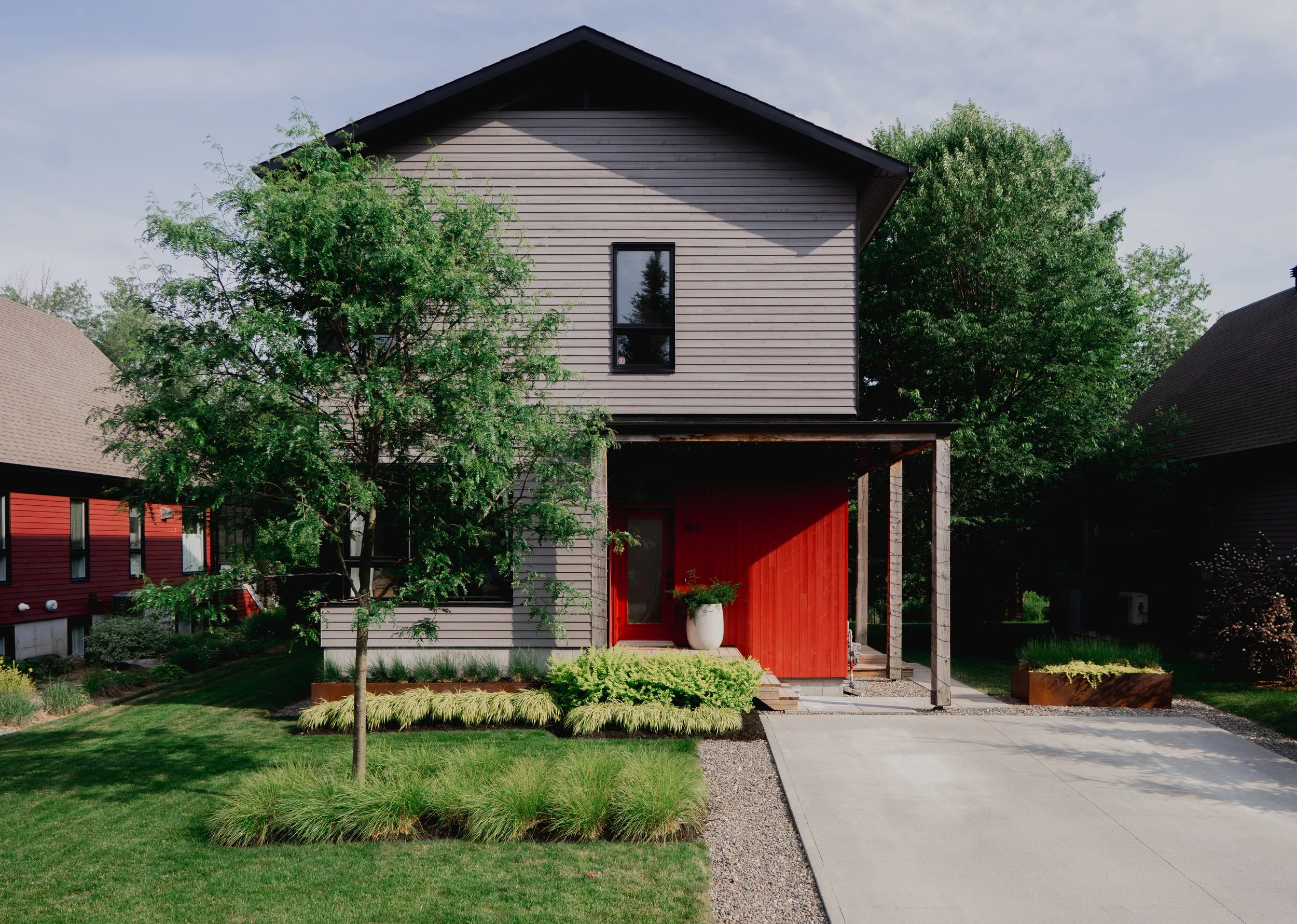 Façade de maison moderne à Bromont avec intégration de béton et végétaux tons-sur-tons