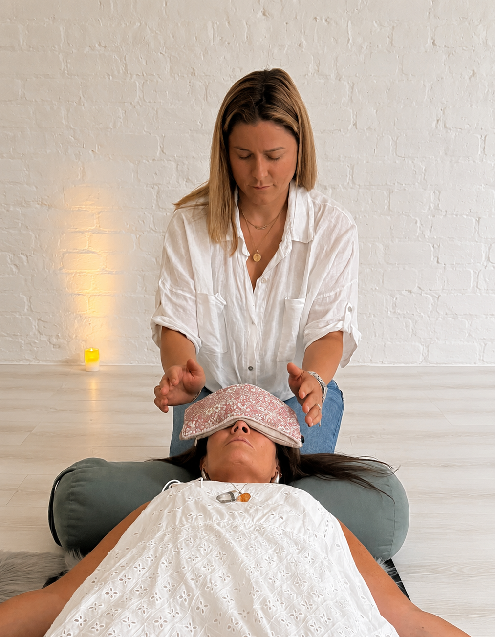 Plum reiki practitioner giving a client reiki while she relaxes on the floor