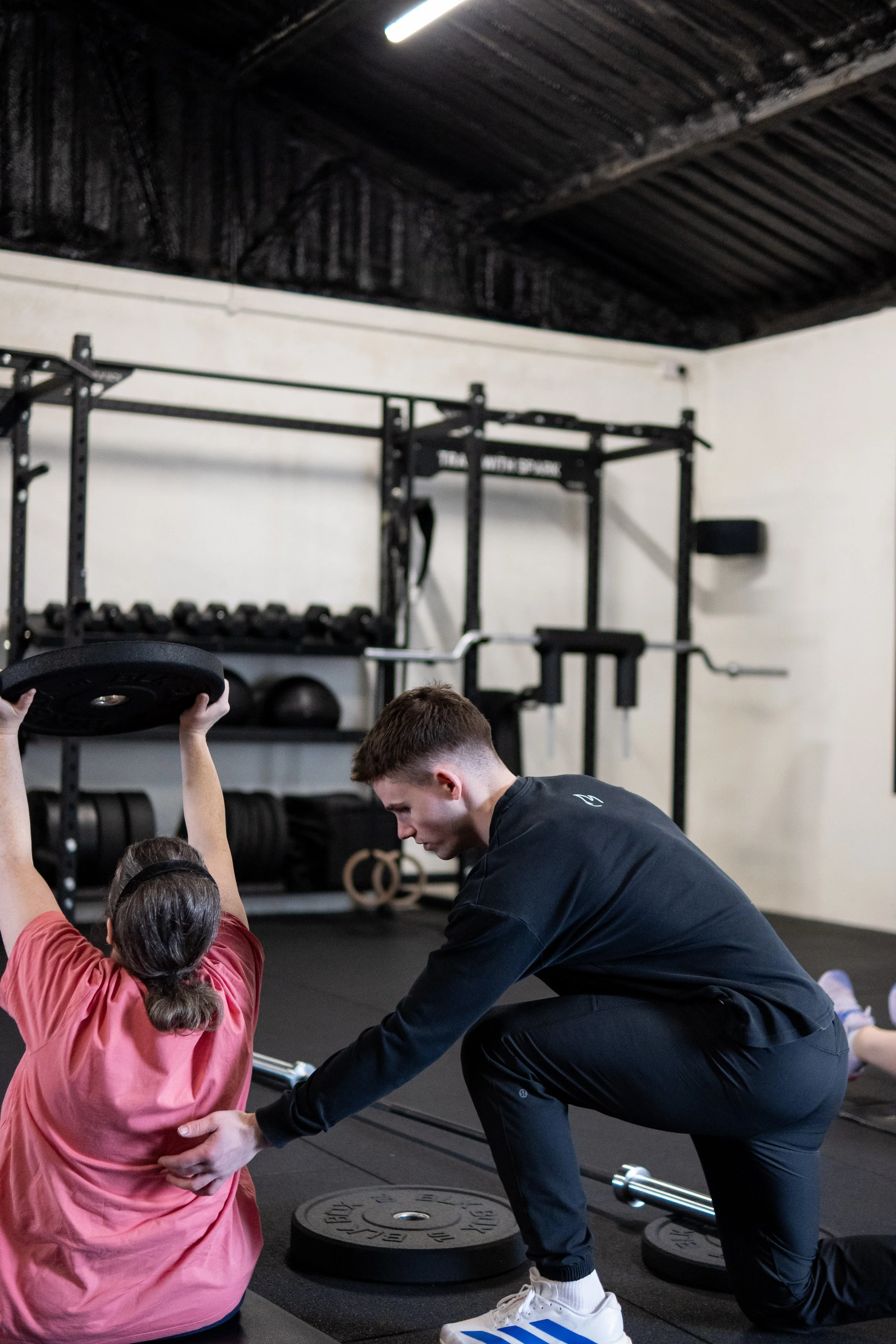 A SPARK coach supporting a member during a strength exercise