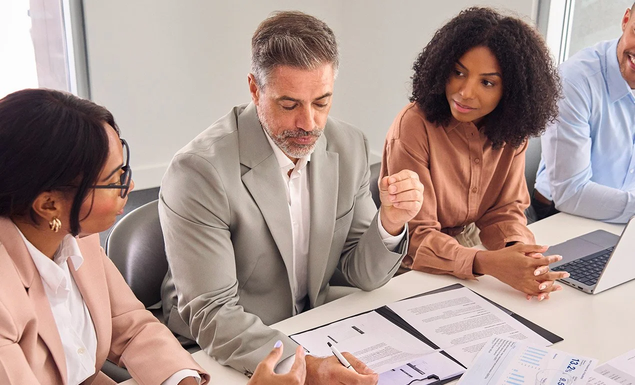 older male executive discussing paperwork with younger professionals