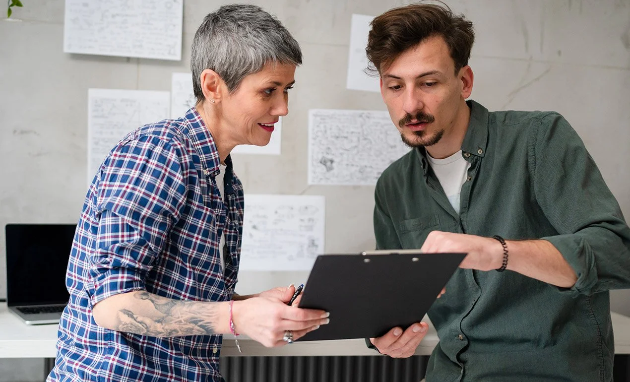 edgy, young co-workers discuss and gesture to tablet
