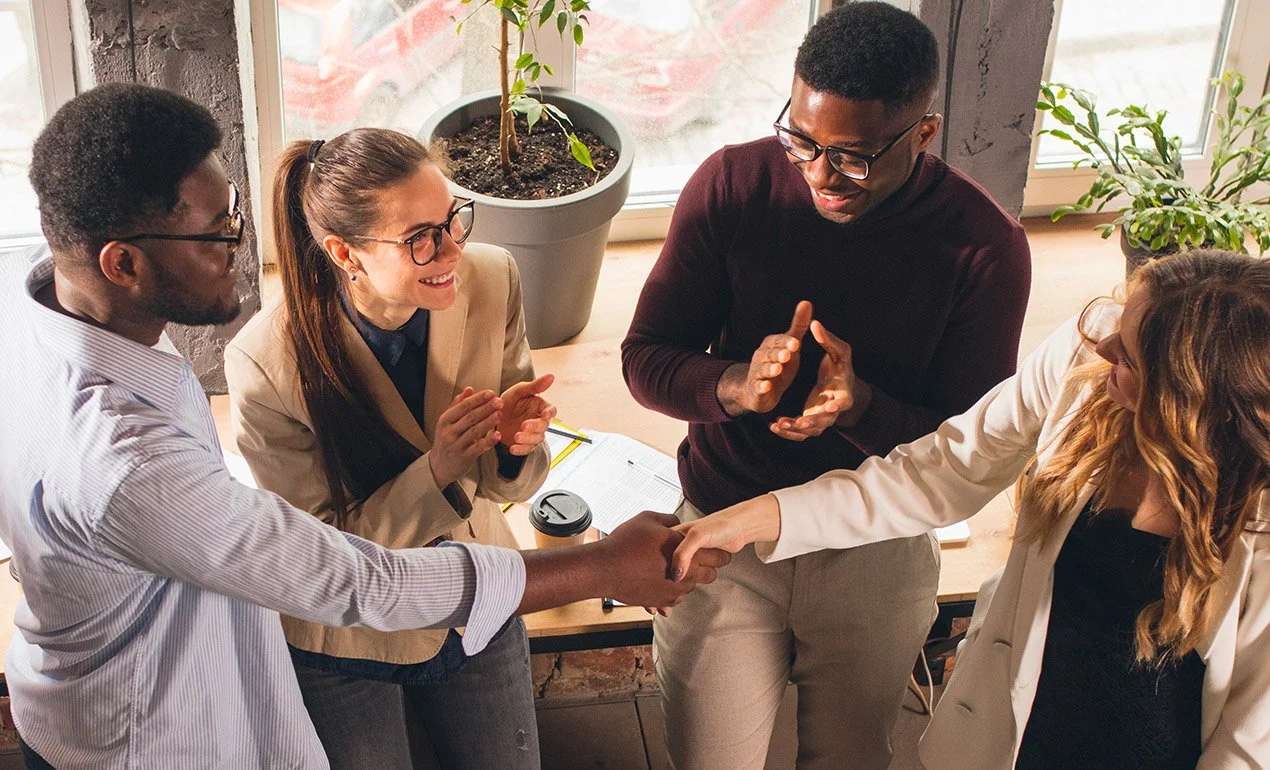 diverse group of 4 co-workers happily meeting each other