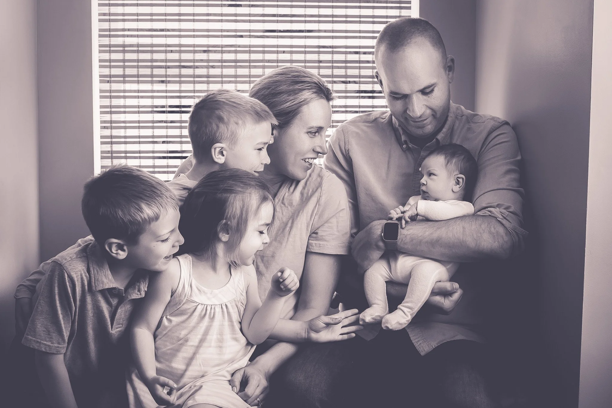 Family of 6 with everyone looking at the newborn baby boy