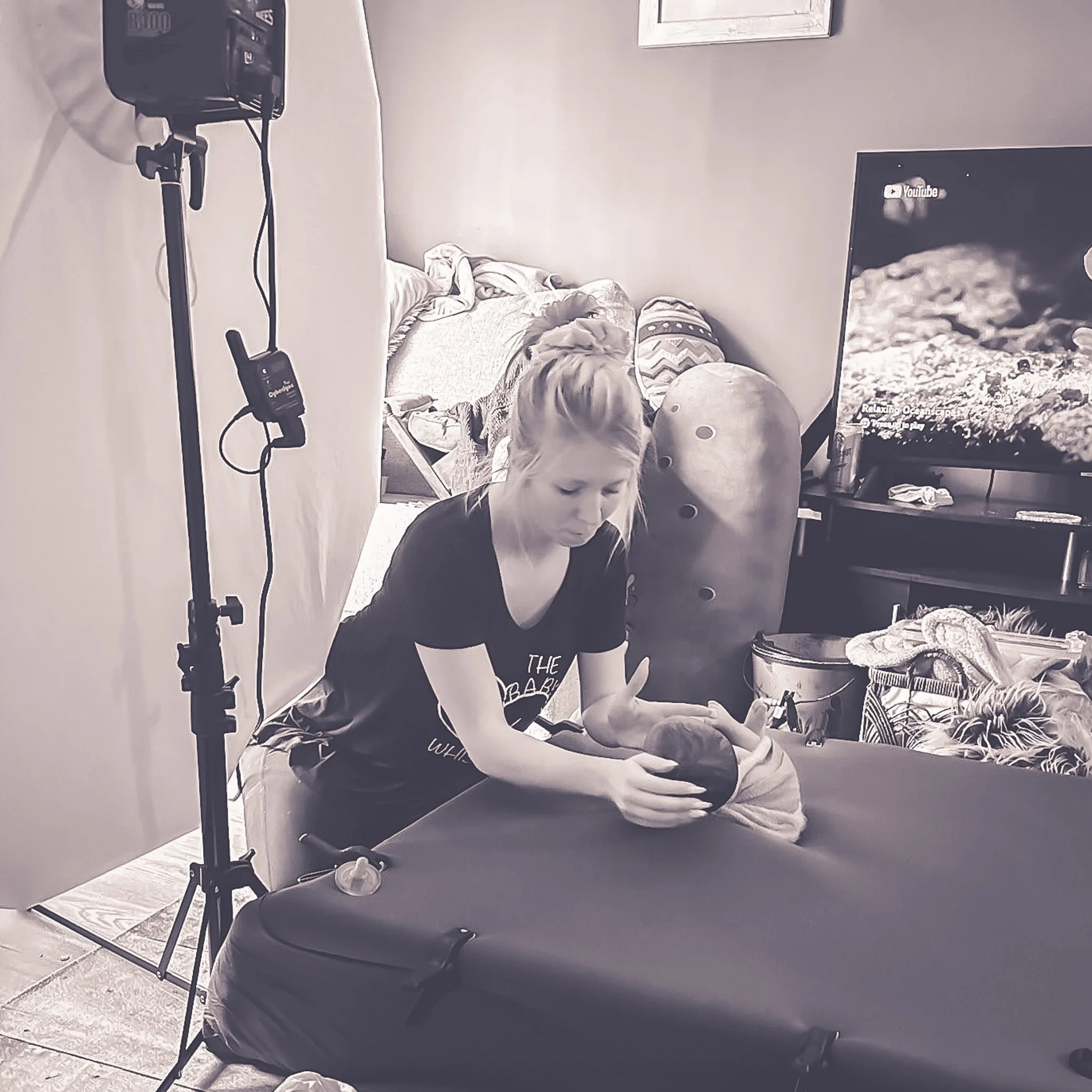 Photographer soothing a newborn baby during an in home photo session