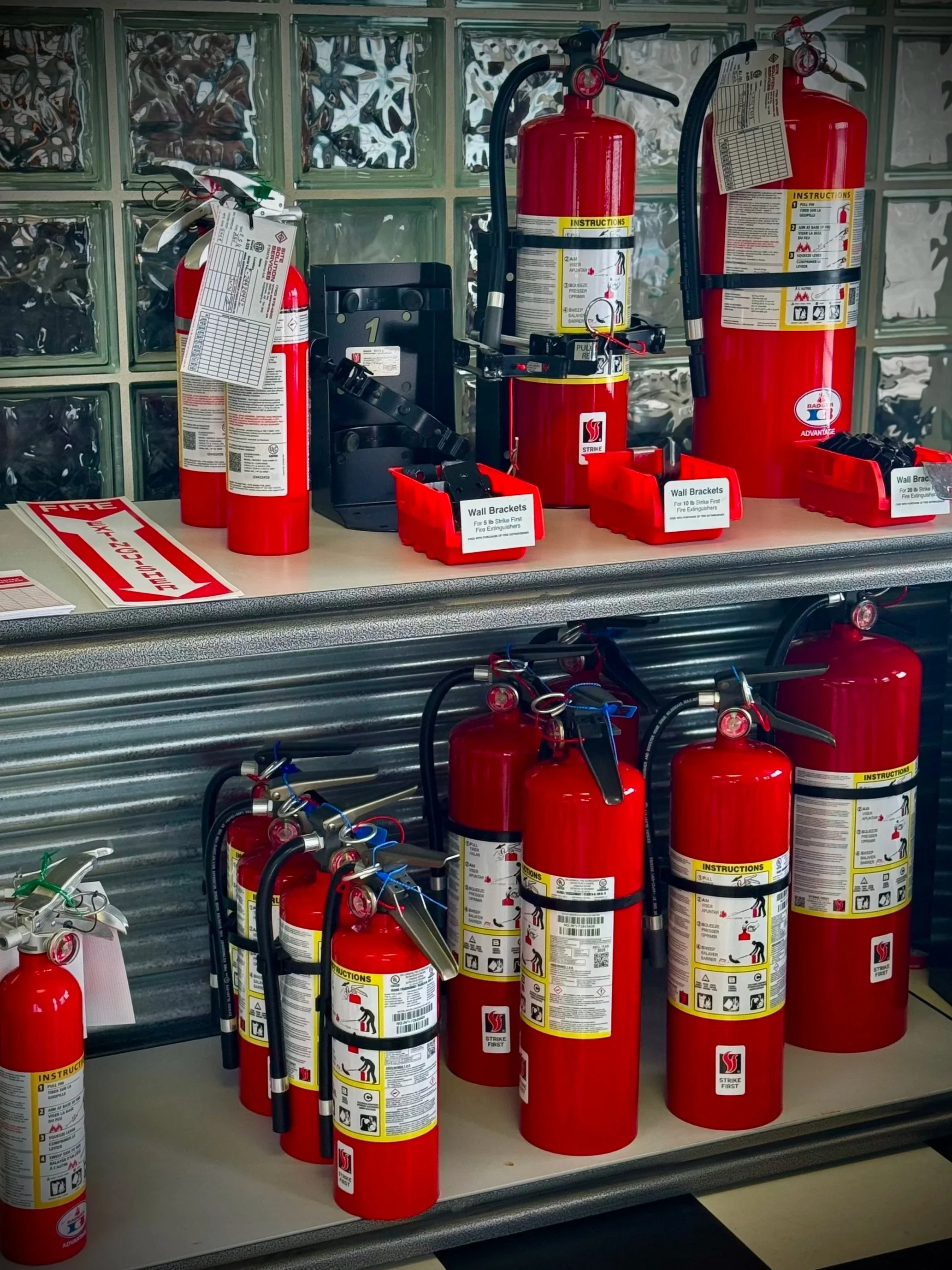 Red fire extinguisher mounted on a safety cabinet with safety signs, including fire hazard, warning, protective equipment, and safety instructions, outdoors.