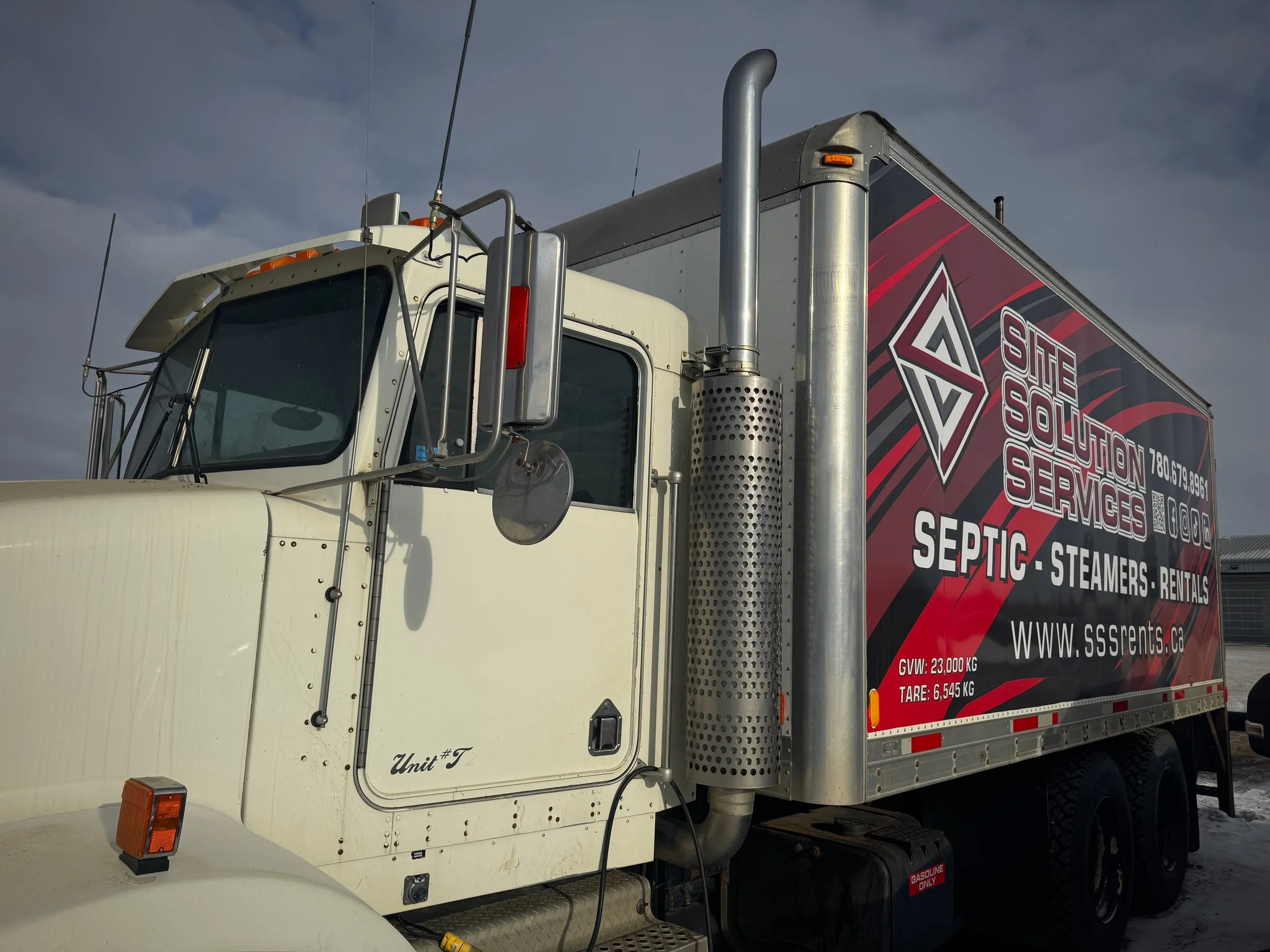 Construction site fence with multiple safety and warning signs, including stop, danger, construction area, caution, warning hard hat area, PPE required, and site solution services banner.