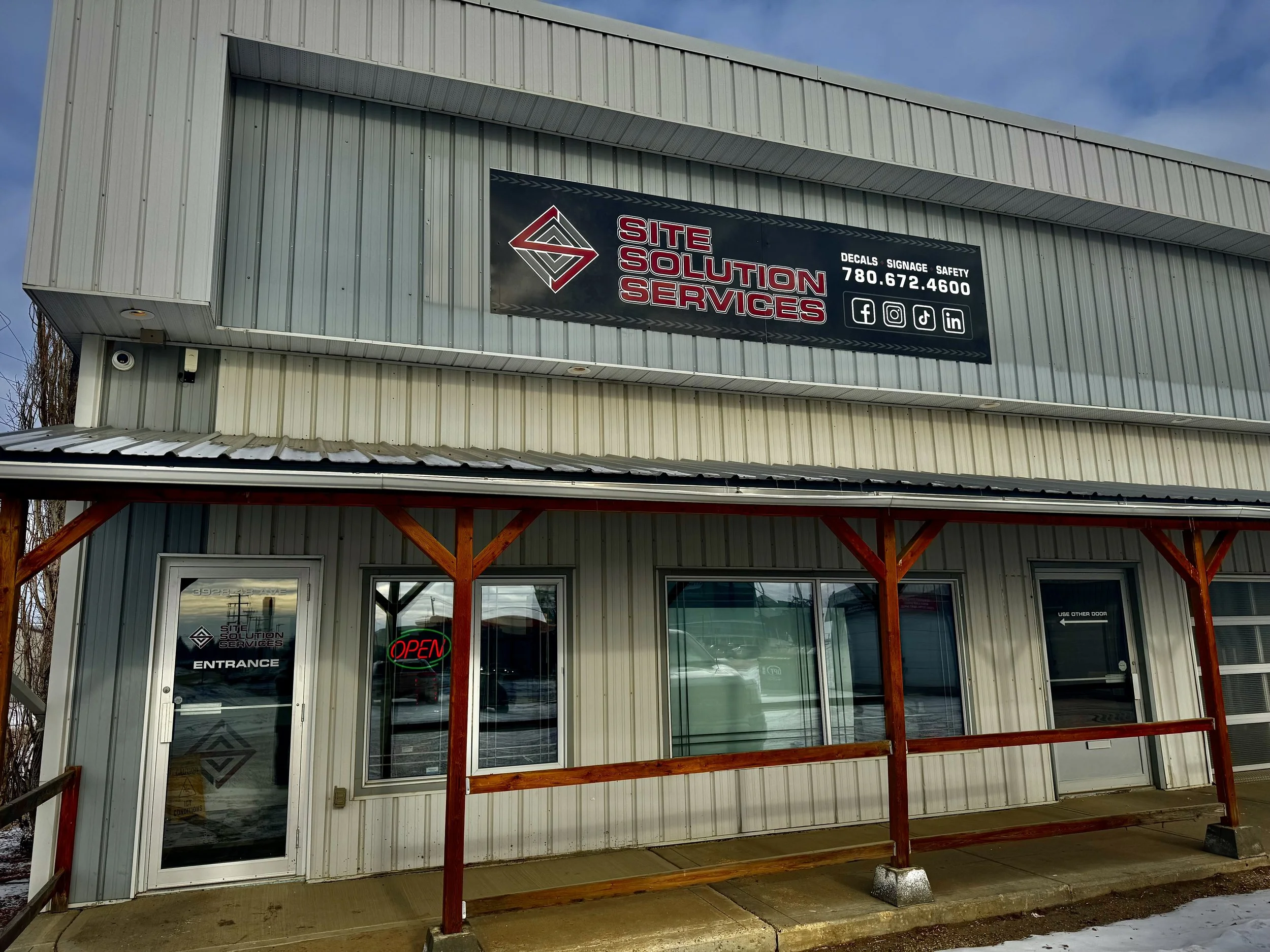 Sign with warning icons, two trucks with the Site Solution Services logo, and a fire extinguisher with the same logo.