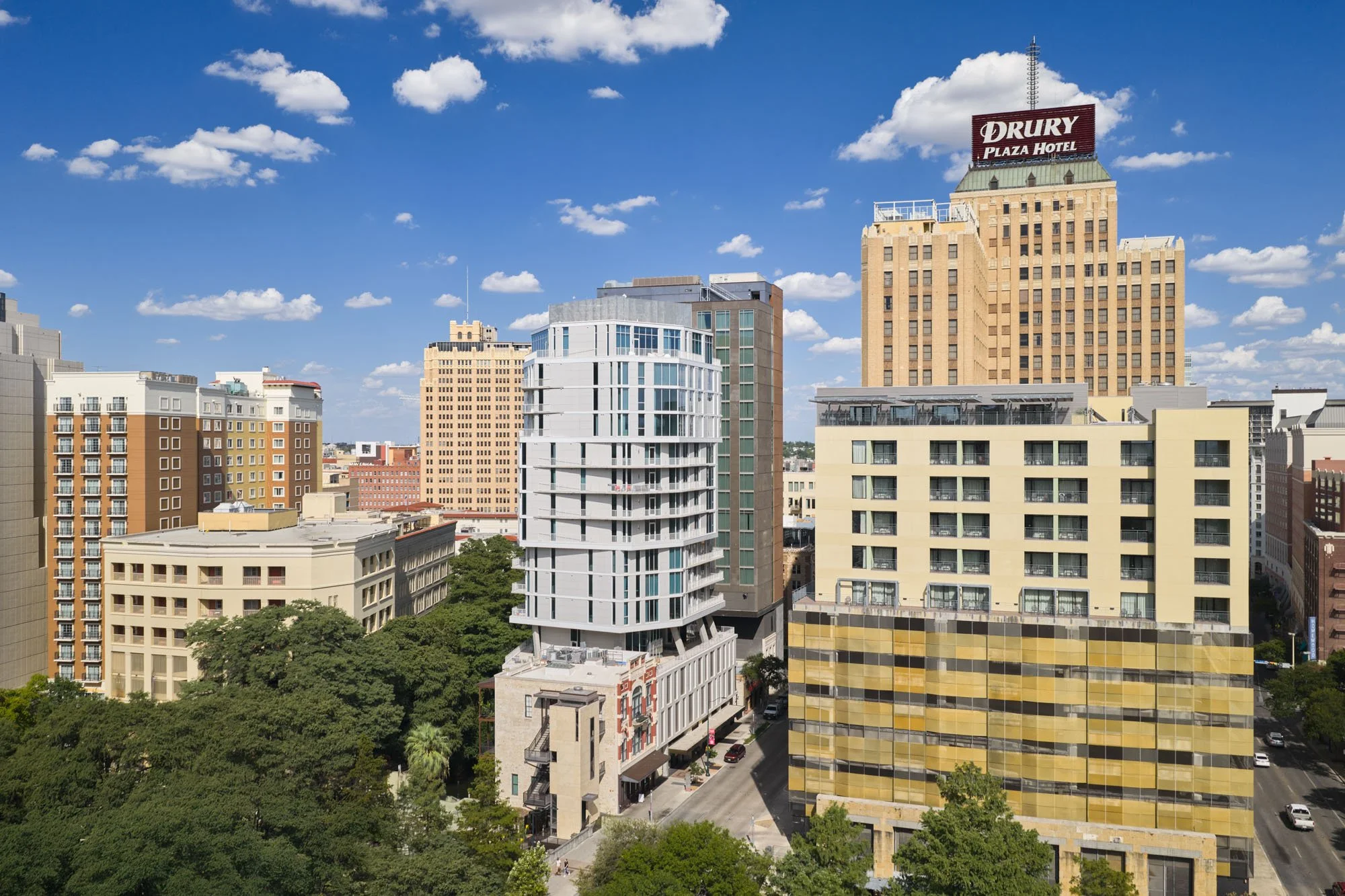 Cityscape with tall buildings under a blue sky with scattered clouds.