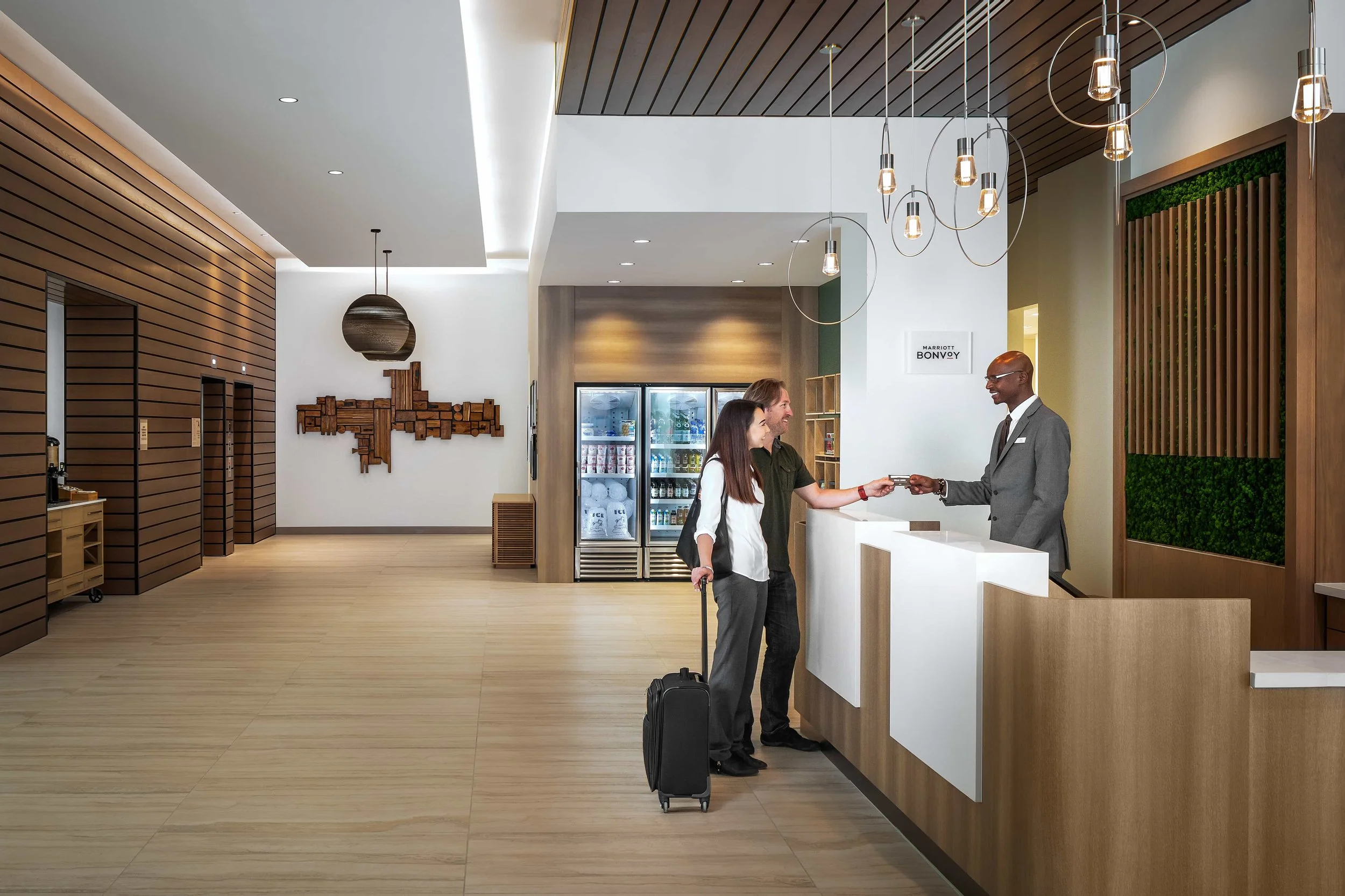 Guests checking in at the hotel reception desk in a modern hotel lobby.