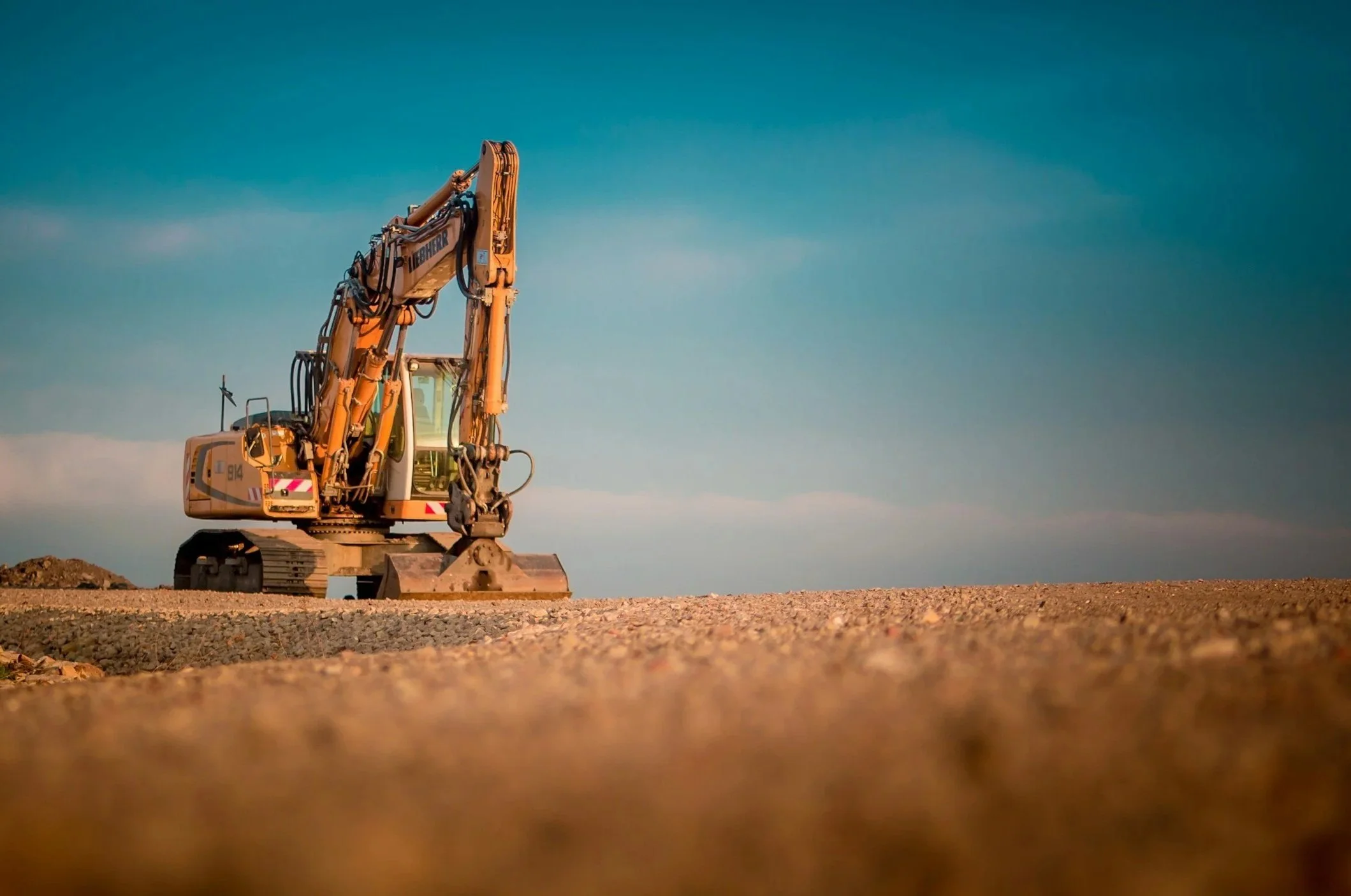 Construction excavator on a dirt construction site with a clear blue sky in the background.