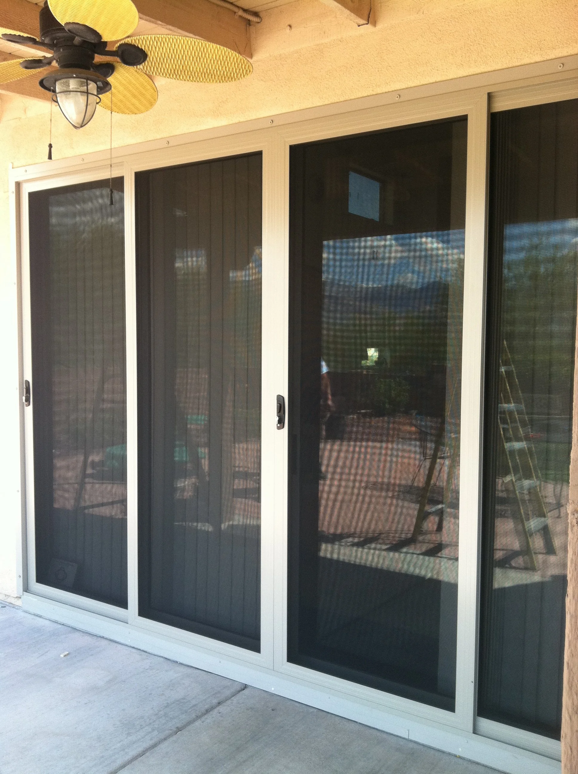 Sliding glass door with black screen door covering. Outside view of patio and mountains in the distance.