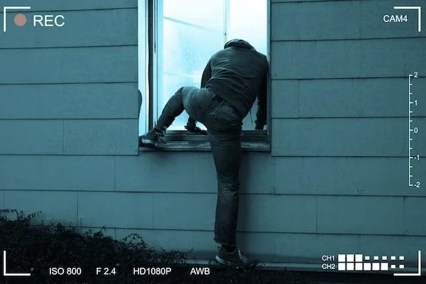 Person climbing out of a window on the exterior of a house.
