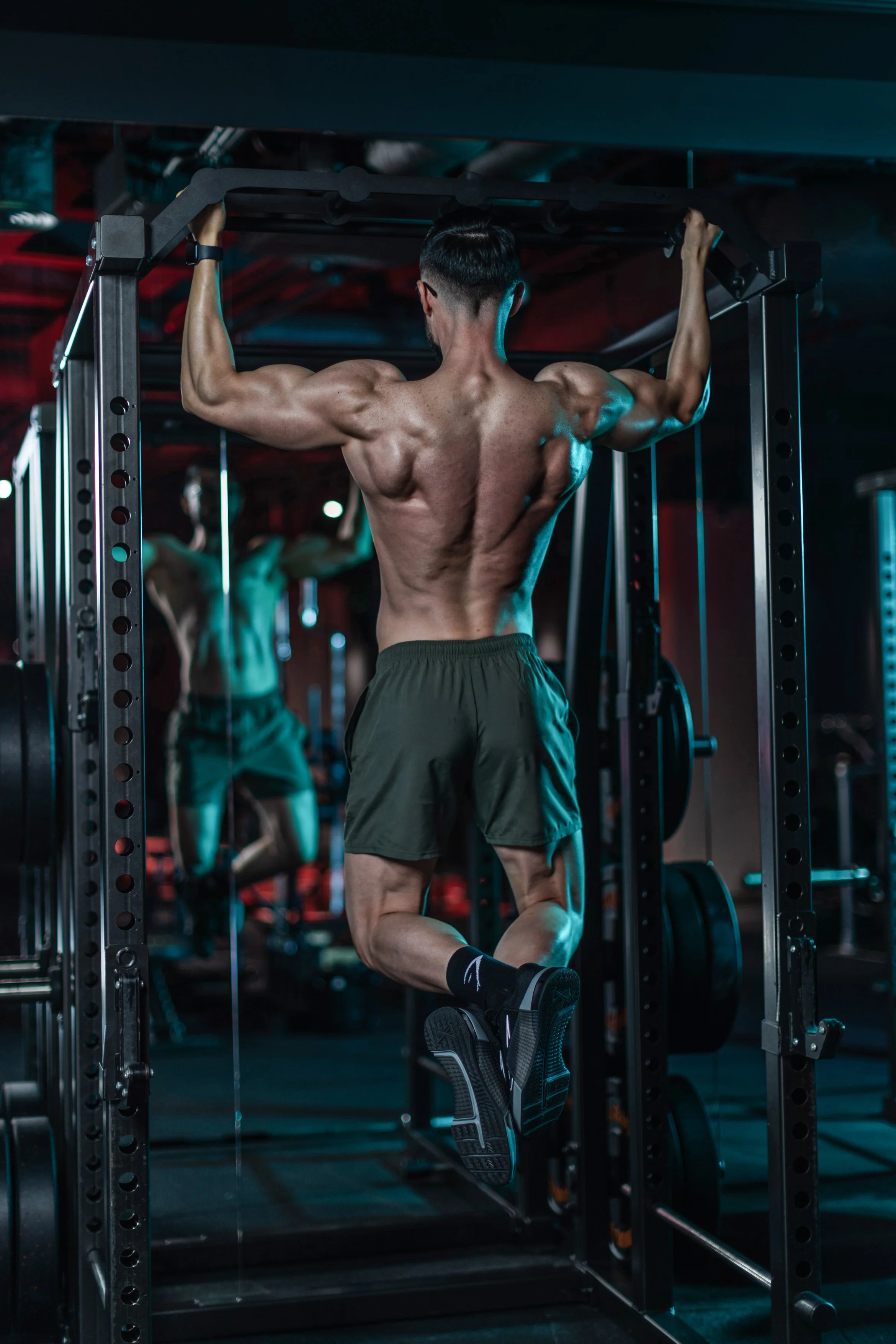 A muscular man doing pull-ups at a gym.
