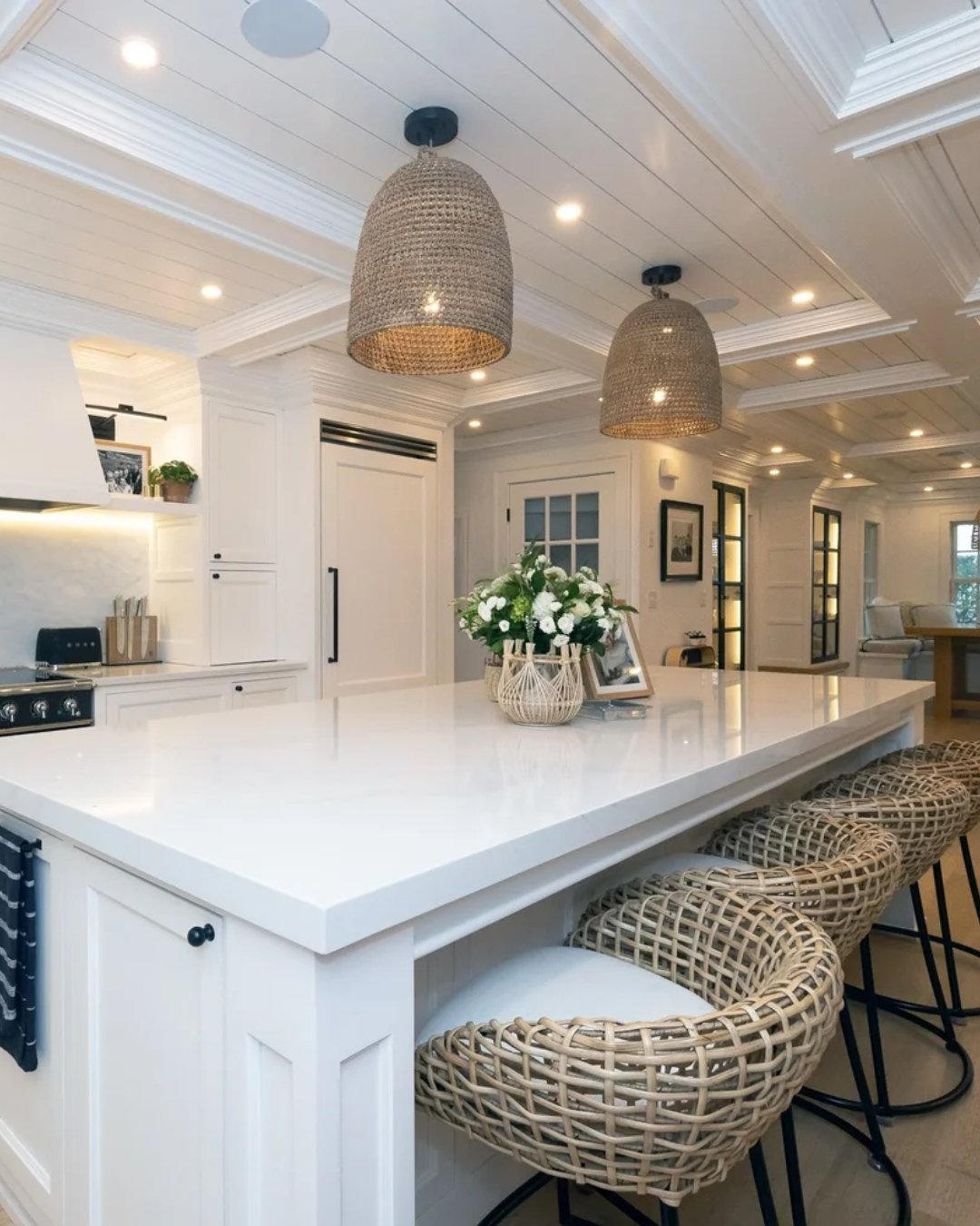 This kitchen is made for gathering. A clean, expansive island anchors the space, paired with warm woven textures and soft lighting that bring everything to life. Classic cabinetry, subtle detailing, and a bright, open layout create a space that feels