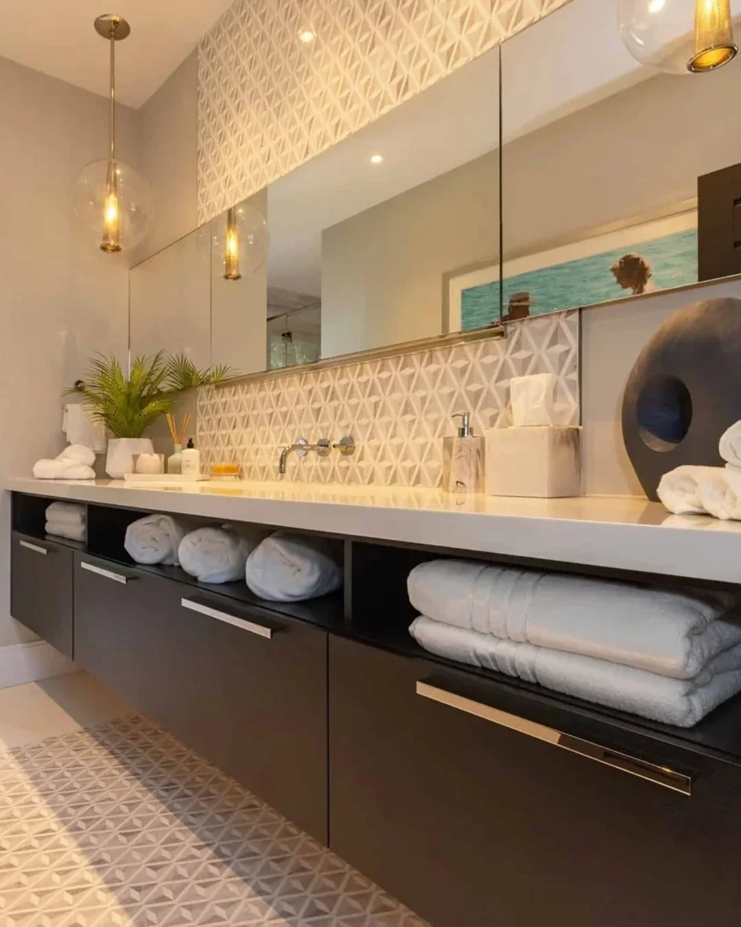 This space is all about balance. Clean lines and warm tones come together with a textured tile backsplash that adds just the right amount of depth. The floating vanity, open shelving, and soft lighting keep it feeling modern, while still warm and inv