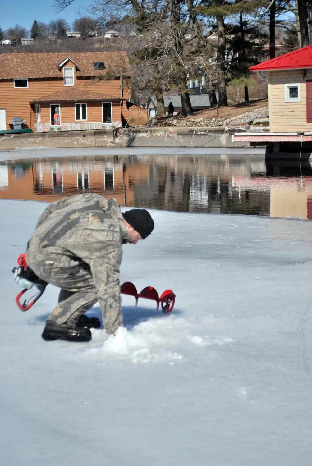 Joe Landolfi checks ice thickness. The edge of the ice in relation to open water is thick.