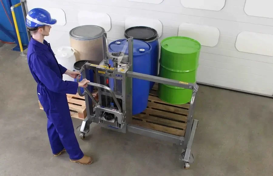 pucture of a person standing with the stainless steel pallet straddling drum lifter holding the hydrayulic pump
